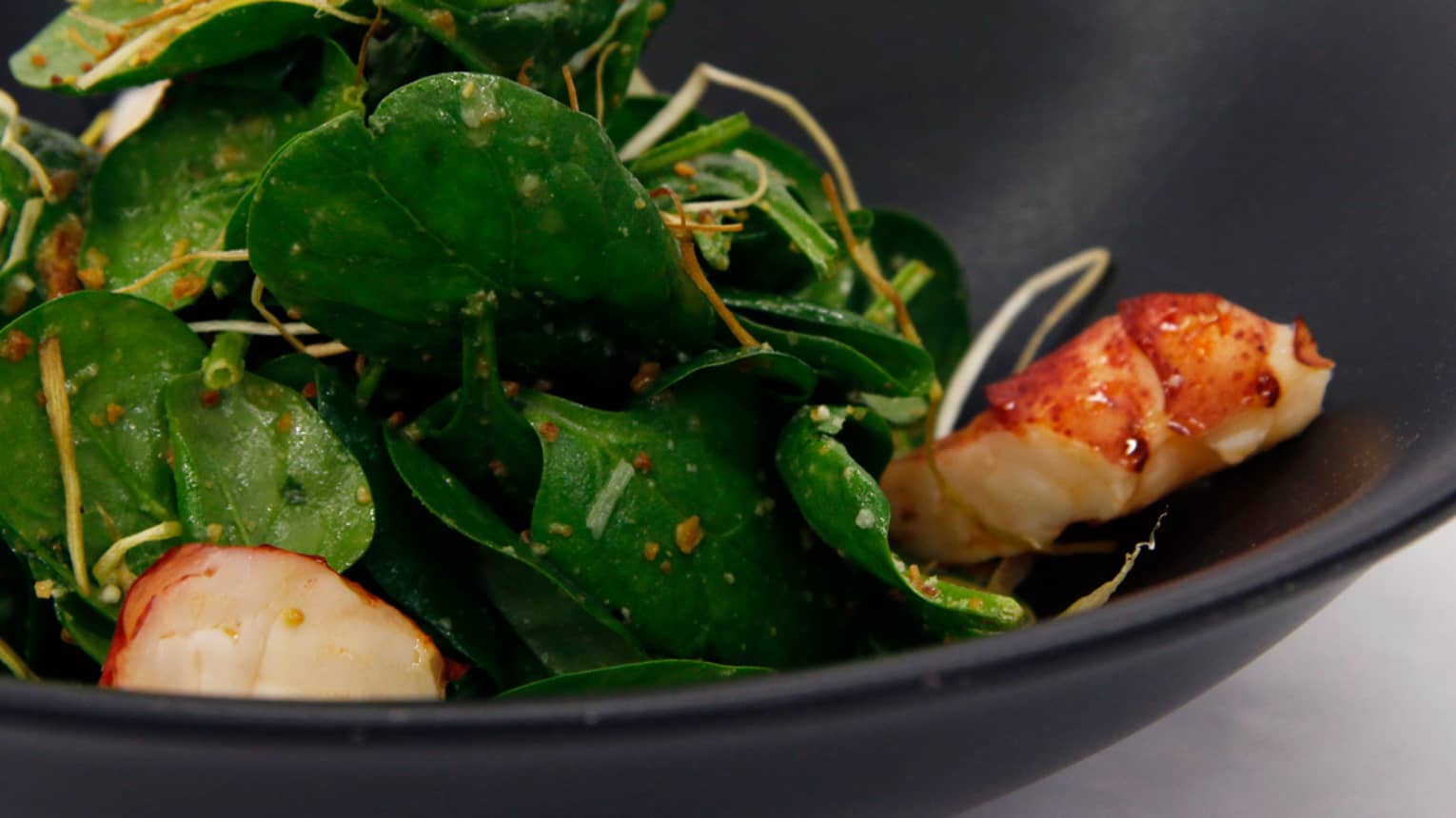 Close-up of Lobster and Spinach Salad with chunks of lobster meat with green leaves, vinaigrette