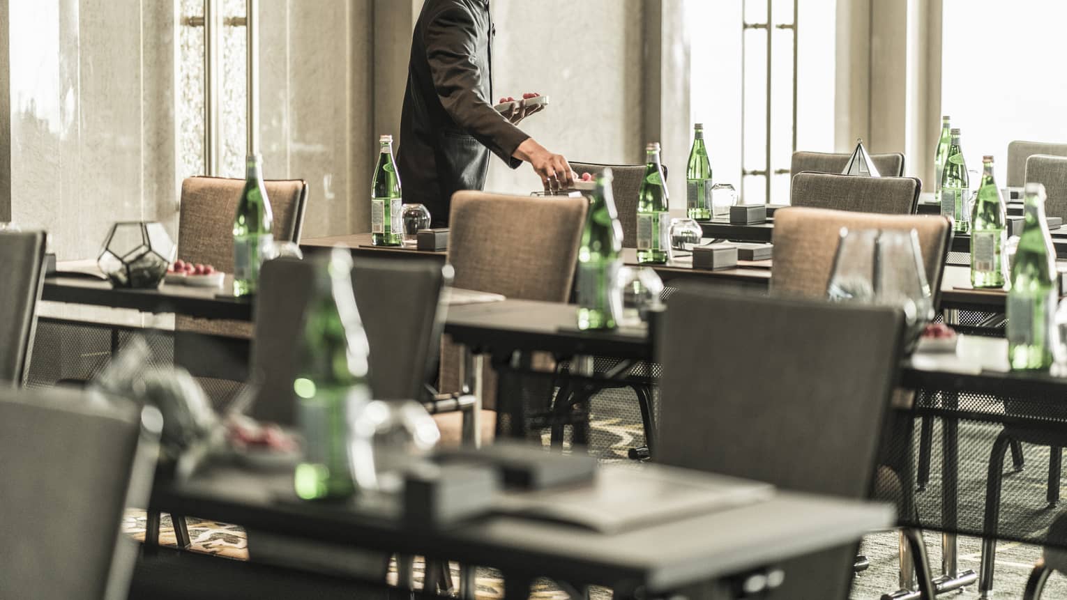 Hotel staff sets rows of conference meeting tables in sunny Junior Ballroom 