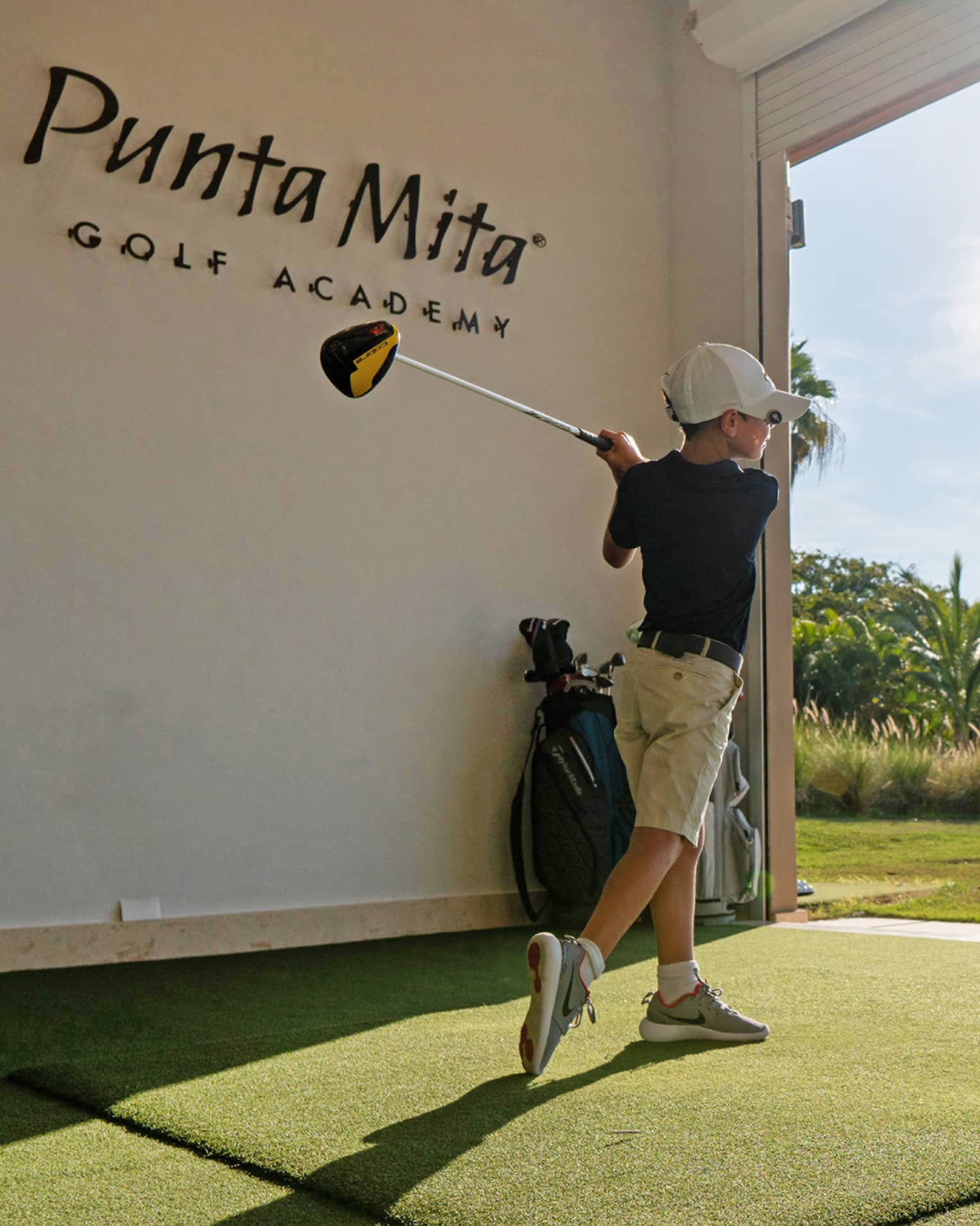 A young child practicing golf in a driving range.
