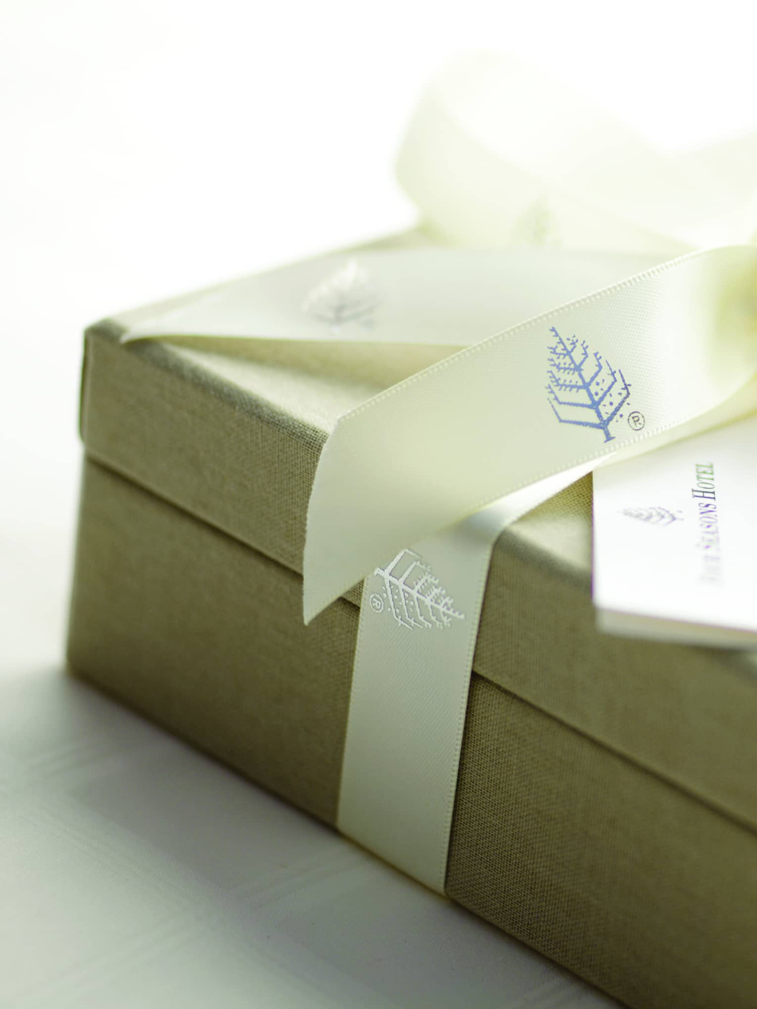 Gift box wrapped up with Four Seasons branded ribbon with a card