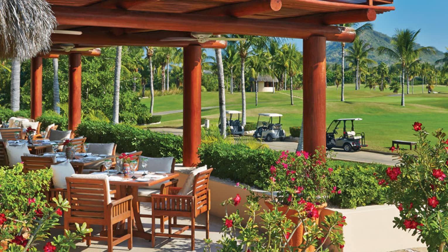 Tail of the Whale patio dining lounge under large wood awning, next to path with white golf carts