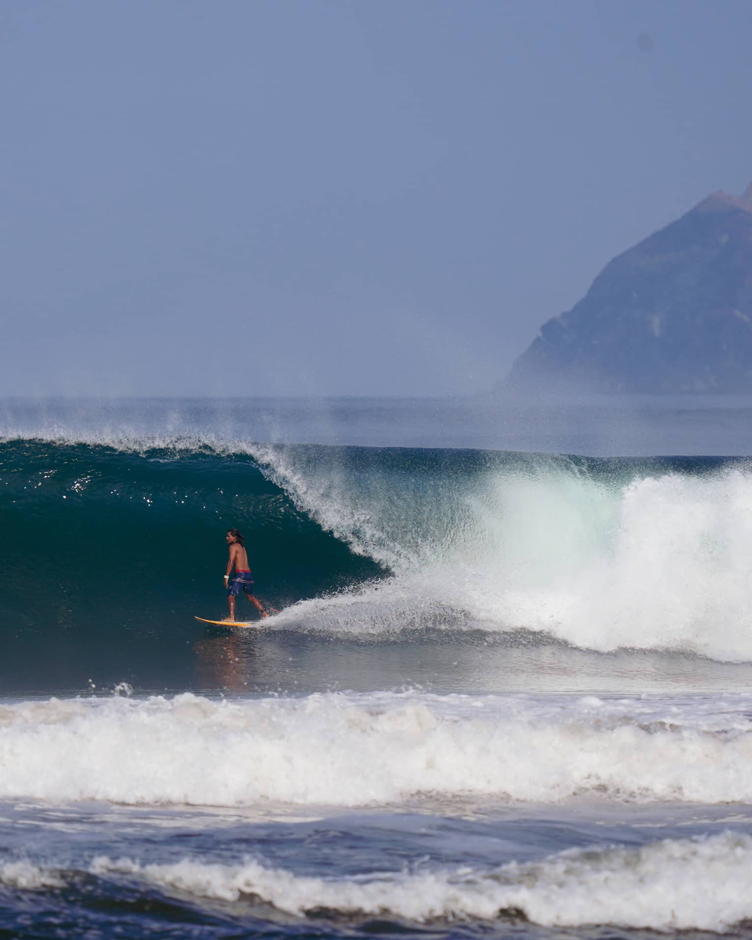 Man surfing under a large wave