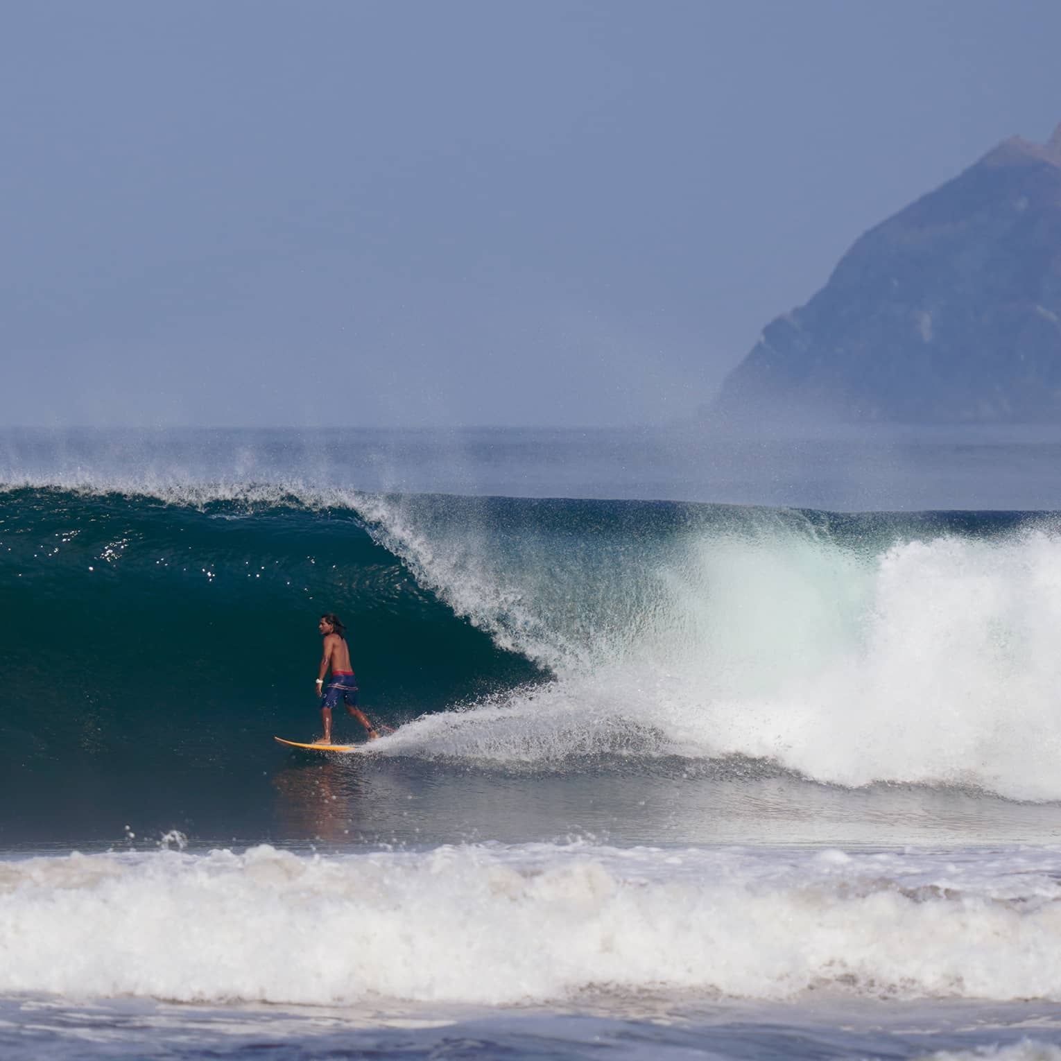 Man surfing under a large wave