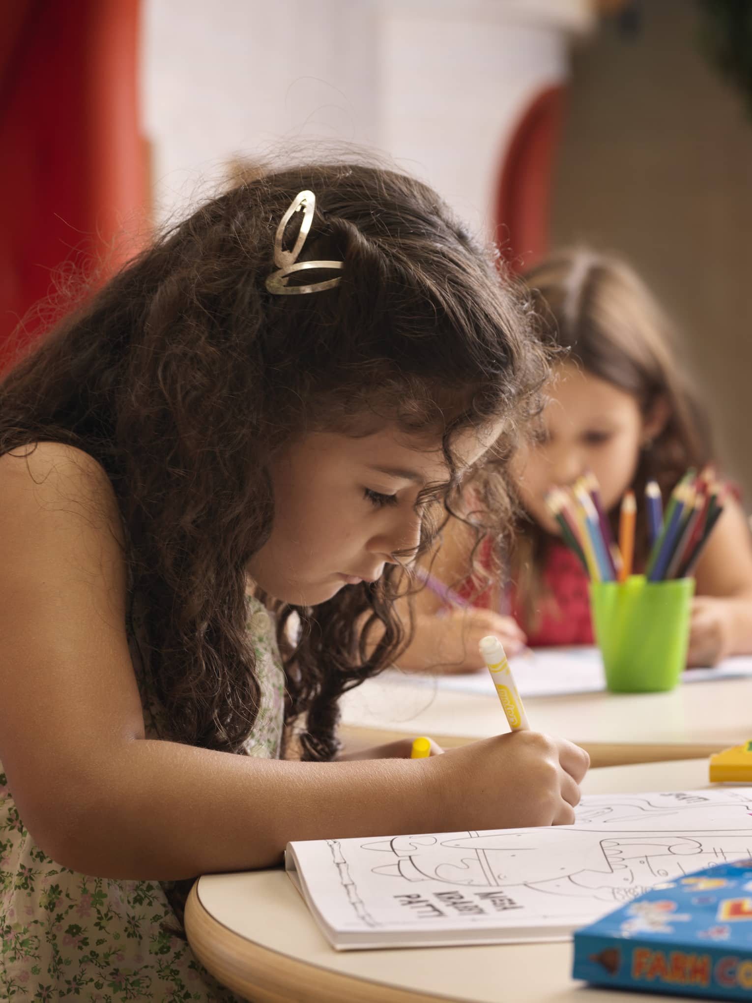 A group of young girls using markers on colouring books.