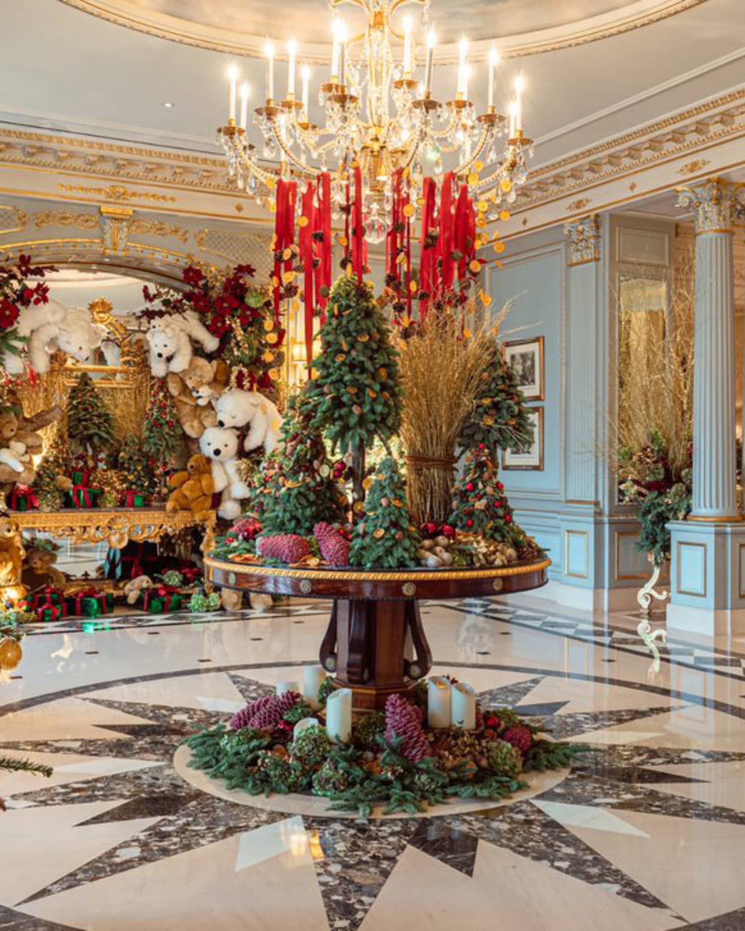 Elegant hotel lobby circular table topped with Christmas tree d�cor under a crystal chandelier