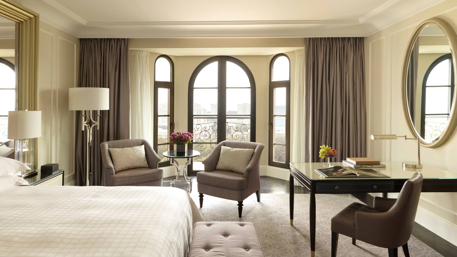 Sunny Deluxe Caspian Room hotel room with arched French doors, two armchairs, desk, bed