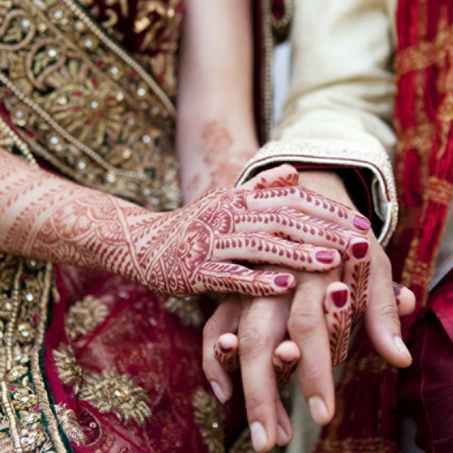 Indian wedding ceremony, bride with henna designs on arm holds groom's hands