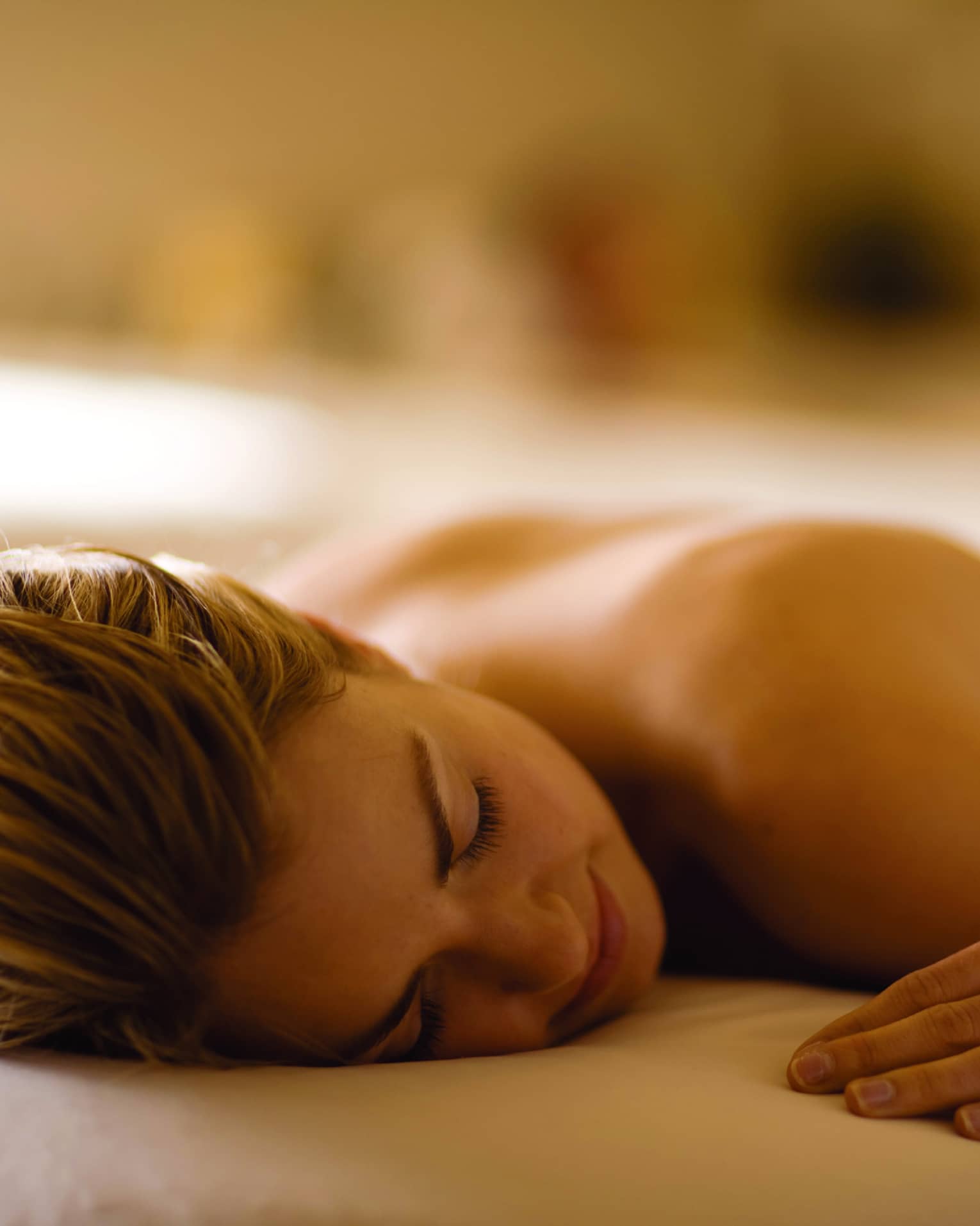 Woman lays with eyes closed, face-down on massage table