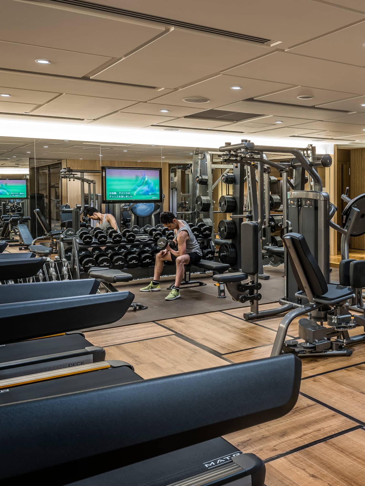 Man sits on bench, lifts weights on Fitness Centre by cardio machines