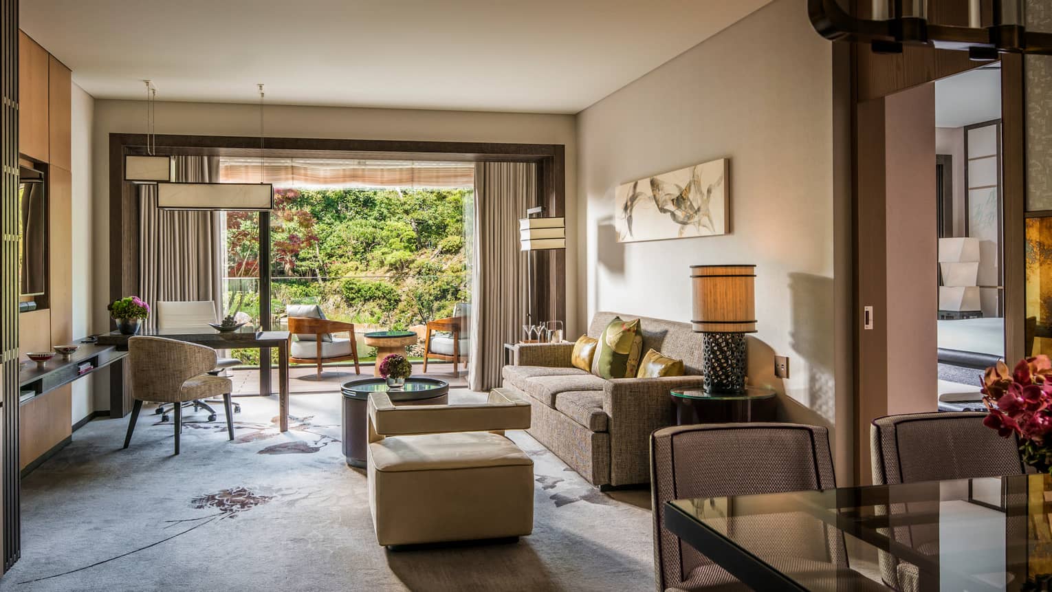 One-bedroom suite large living room desk in front of open balcony sliding doors, patio chairs