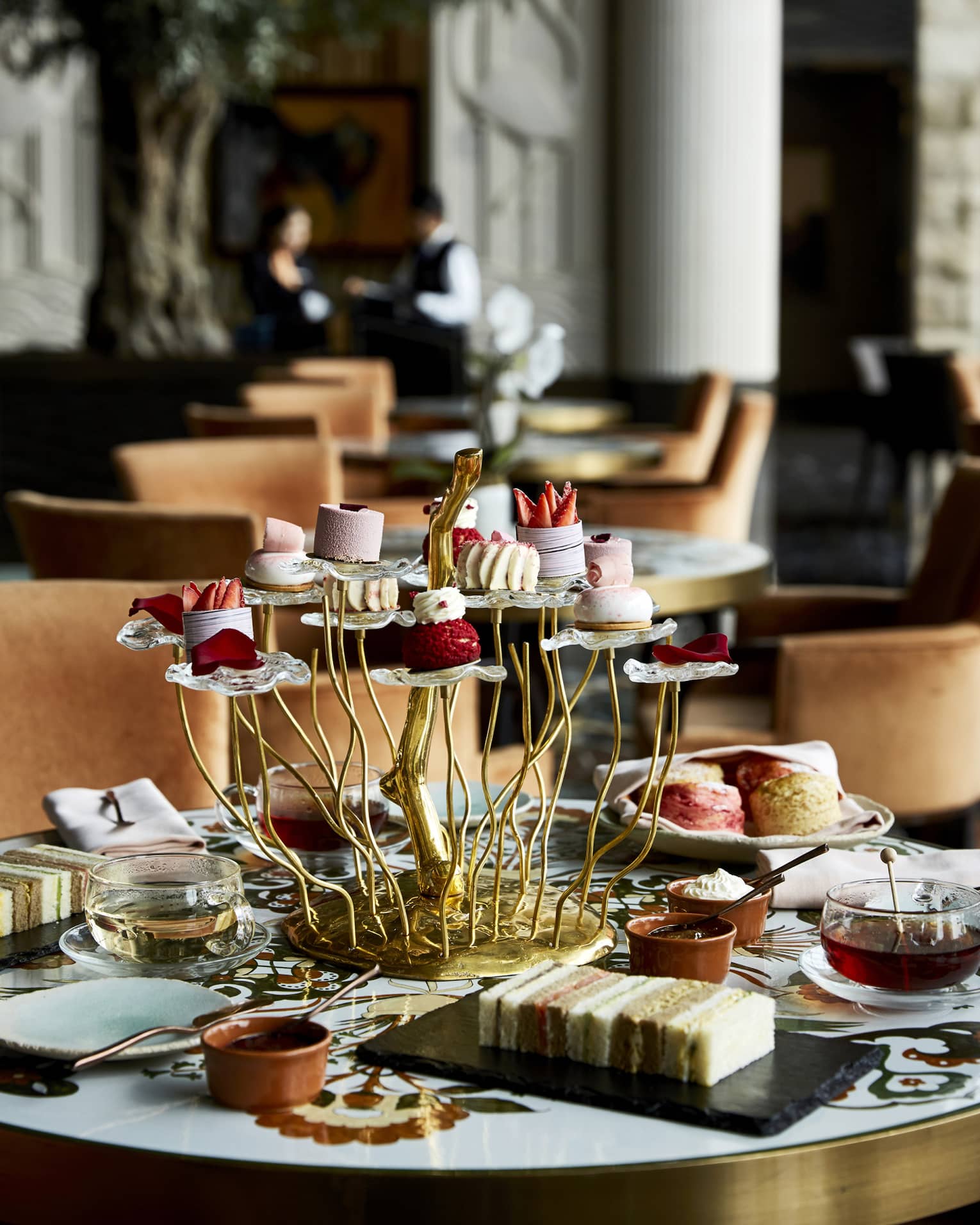 A decadent tea spread consisting of tiered trays of findger foods, trays of desserts and tea