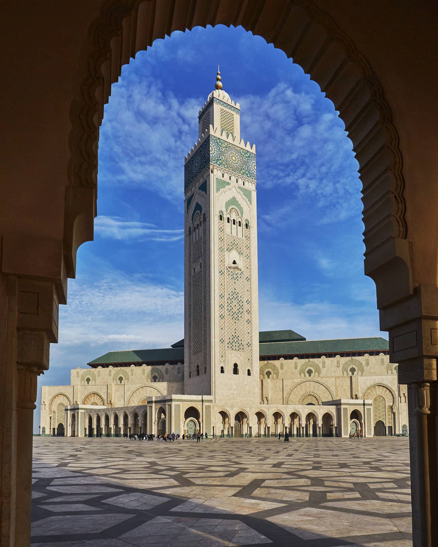 View from archway of Hassan II Mosque tall tower against blue sky