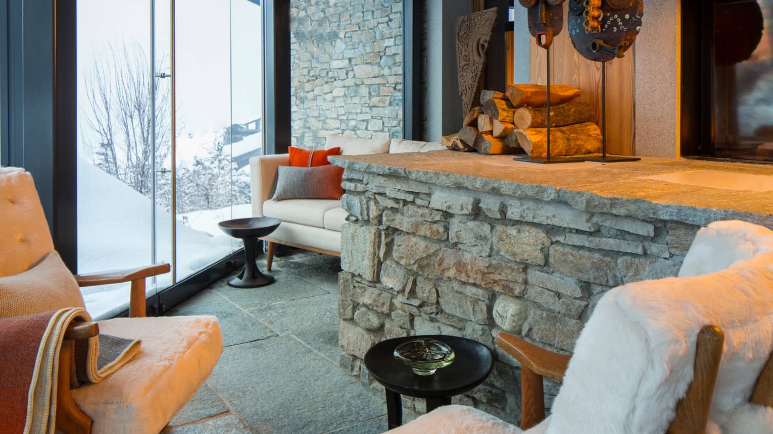 Cigar Room plush white lounge chairs by stone ledge with logs, sculptures, gas fireplace