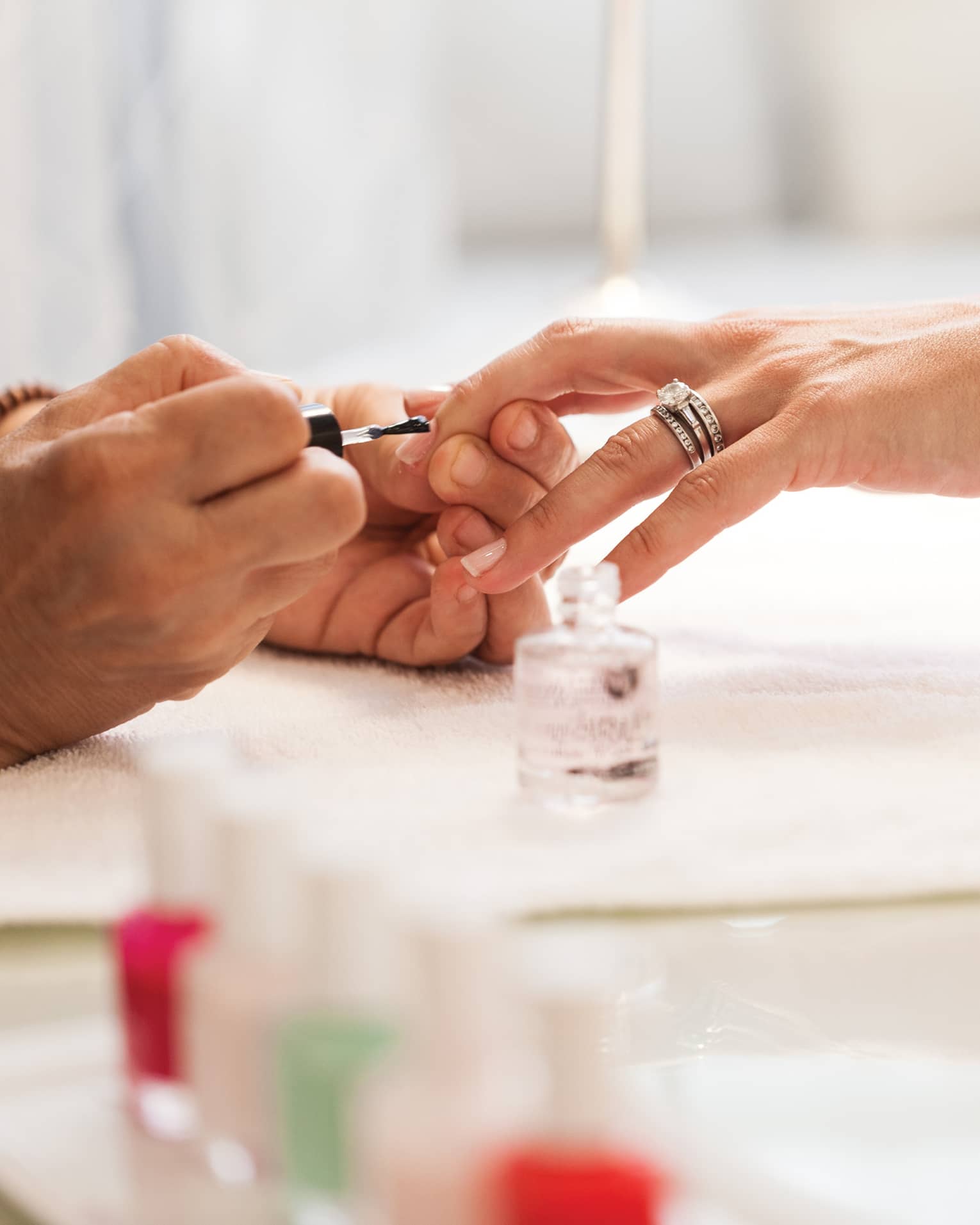 Close-up of woman in white robe getting clear polish manicure at spa table