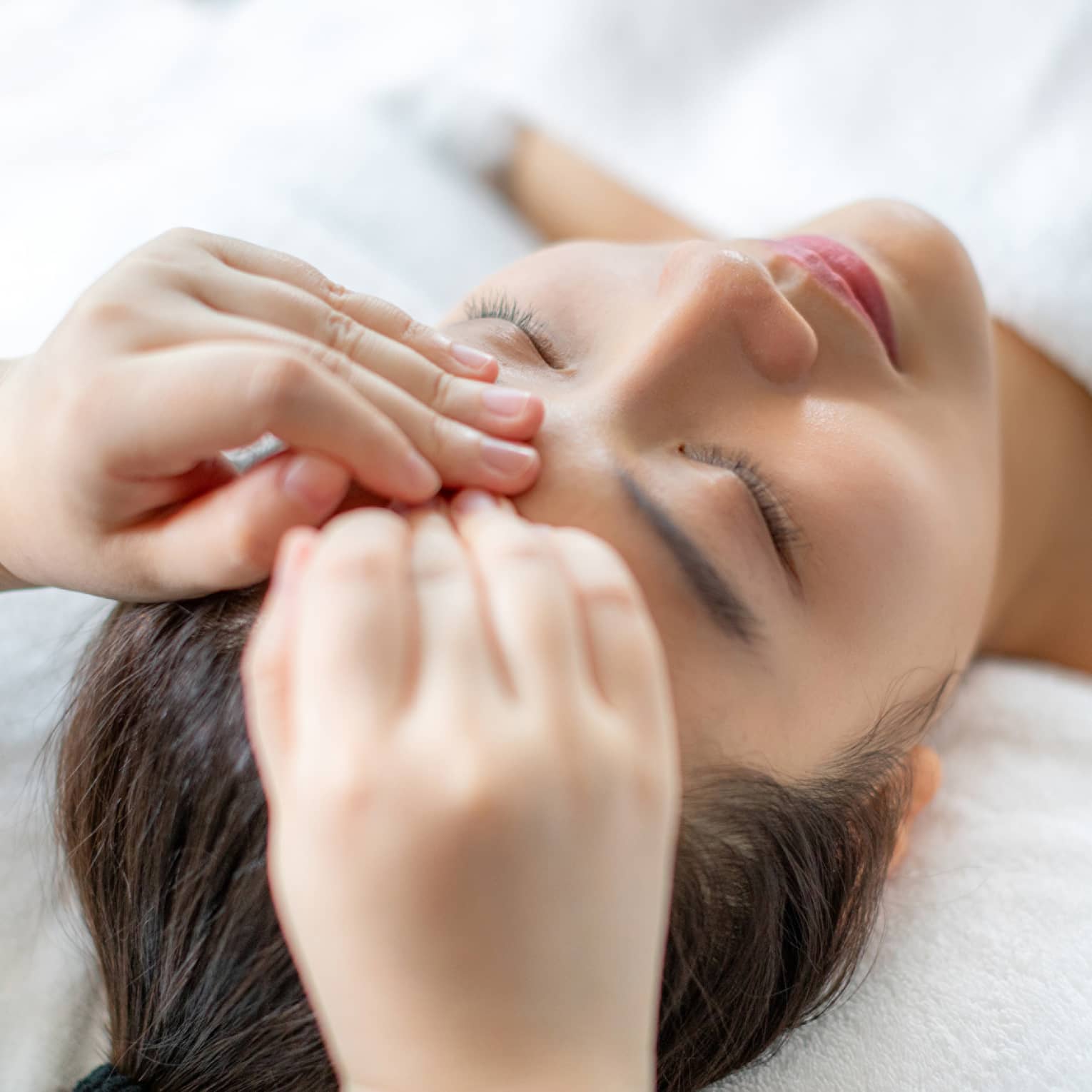 A woman getting a facial massage in a spa.