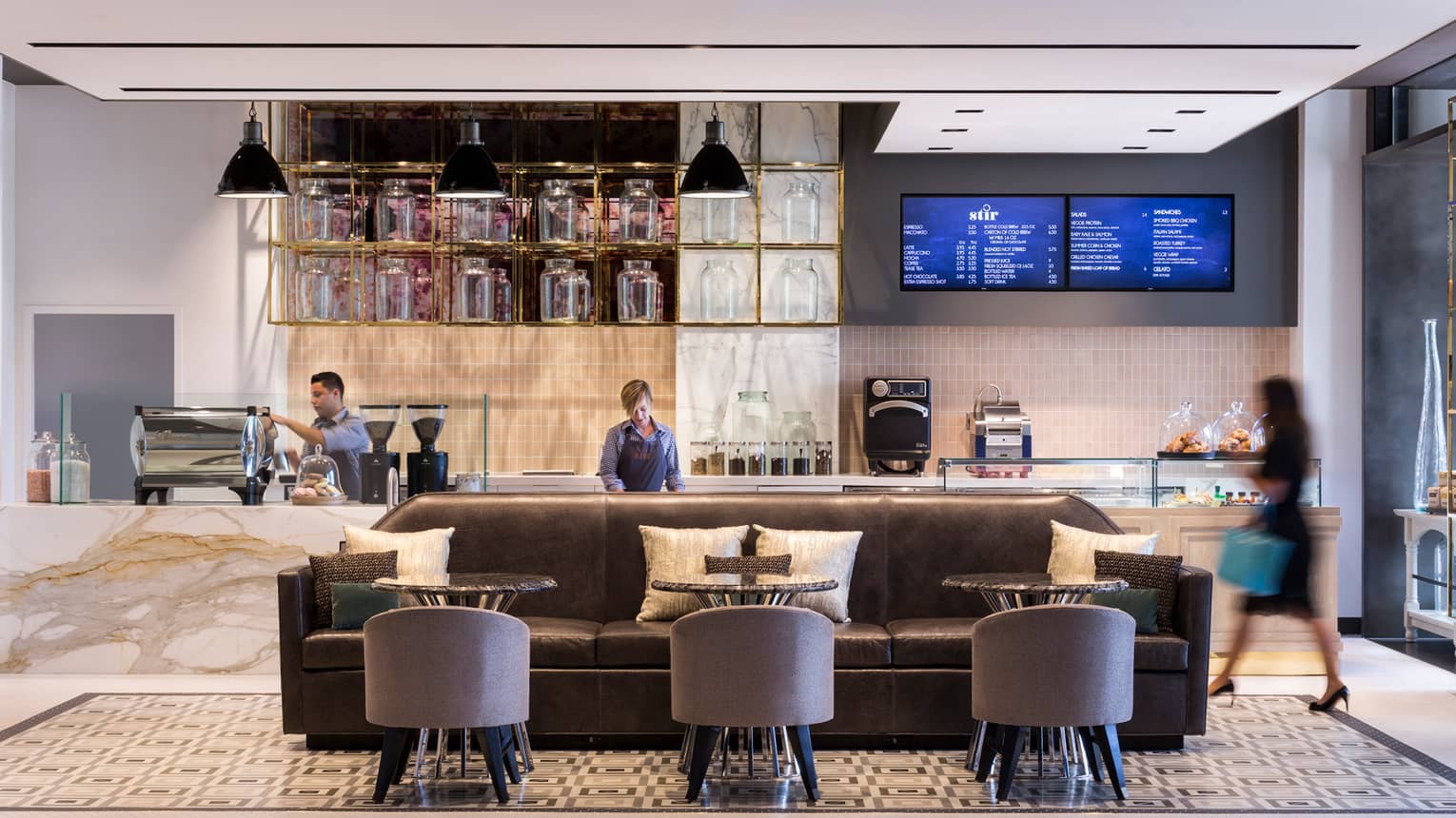 Three staff members at different stations in contemporary Stir lounge, brown sofa with three round tables and club chairs