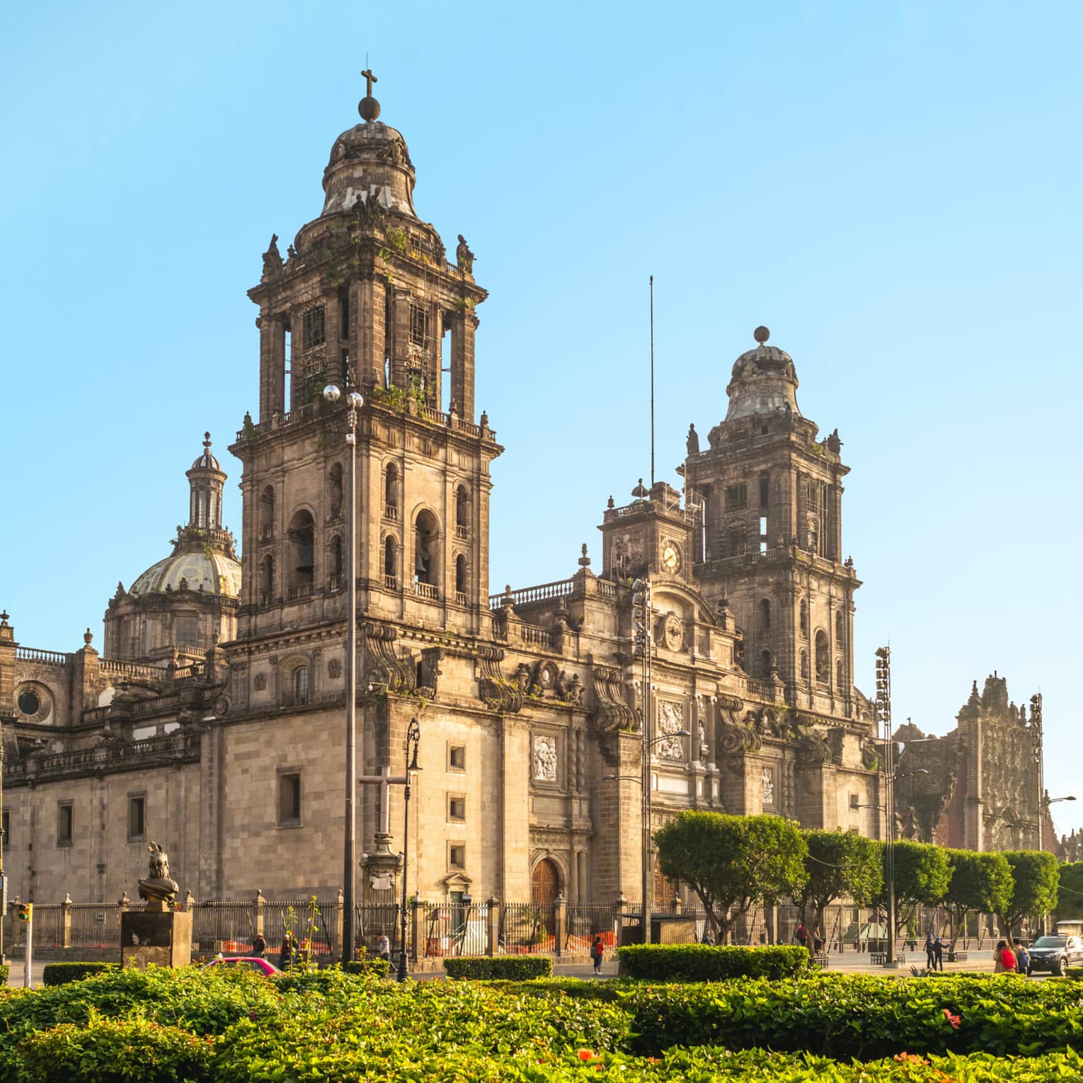 A large old building surrounded by streets and plants.