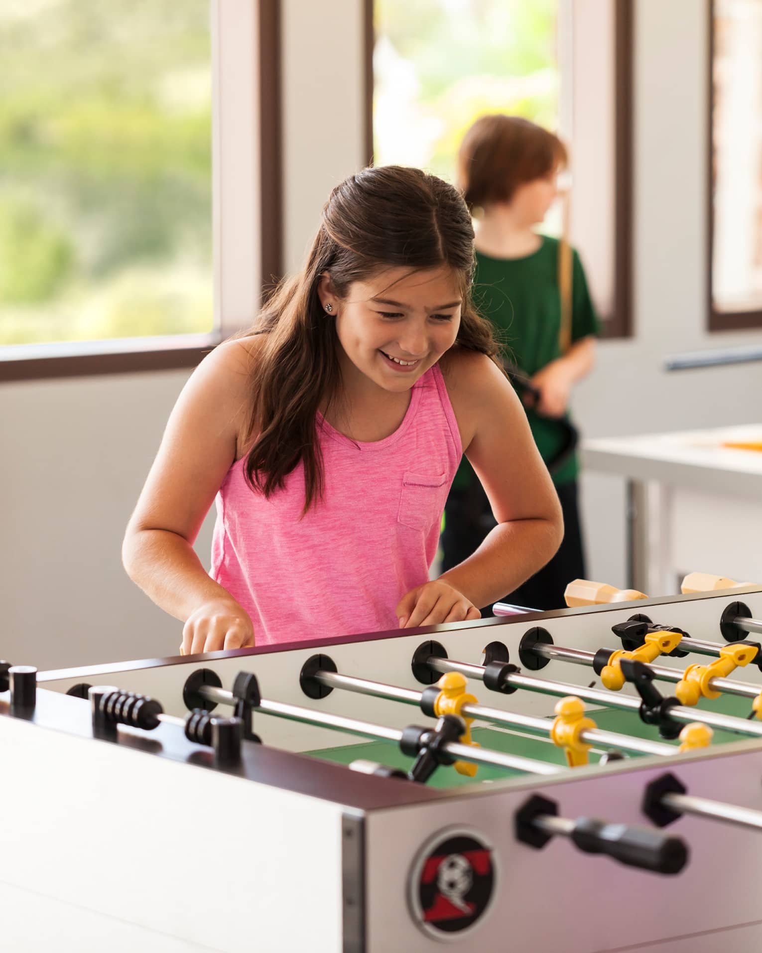 Young teens play table soccer in sunny Teen Centre activity room