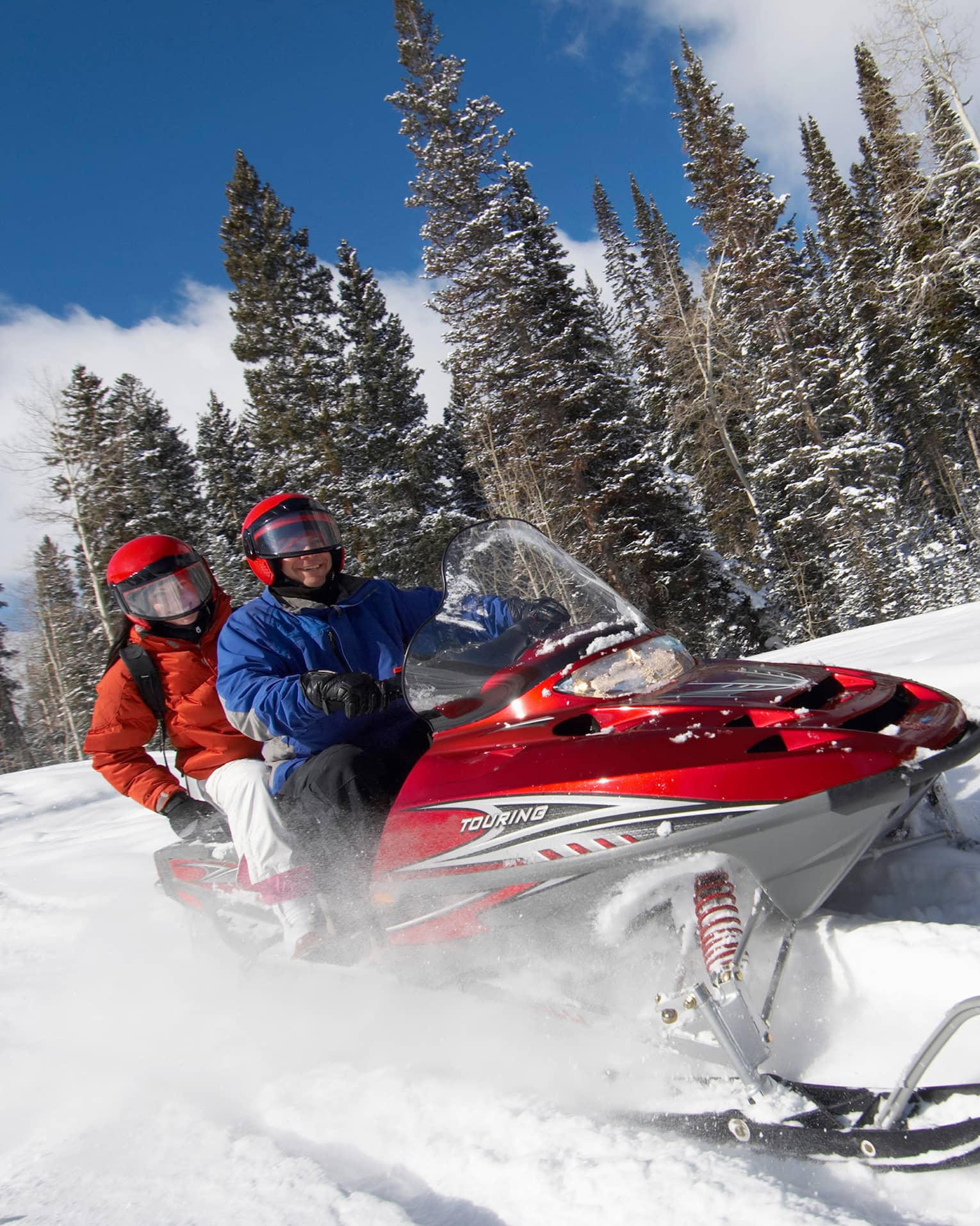 Two people on a snow-mobile racing through snow.