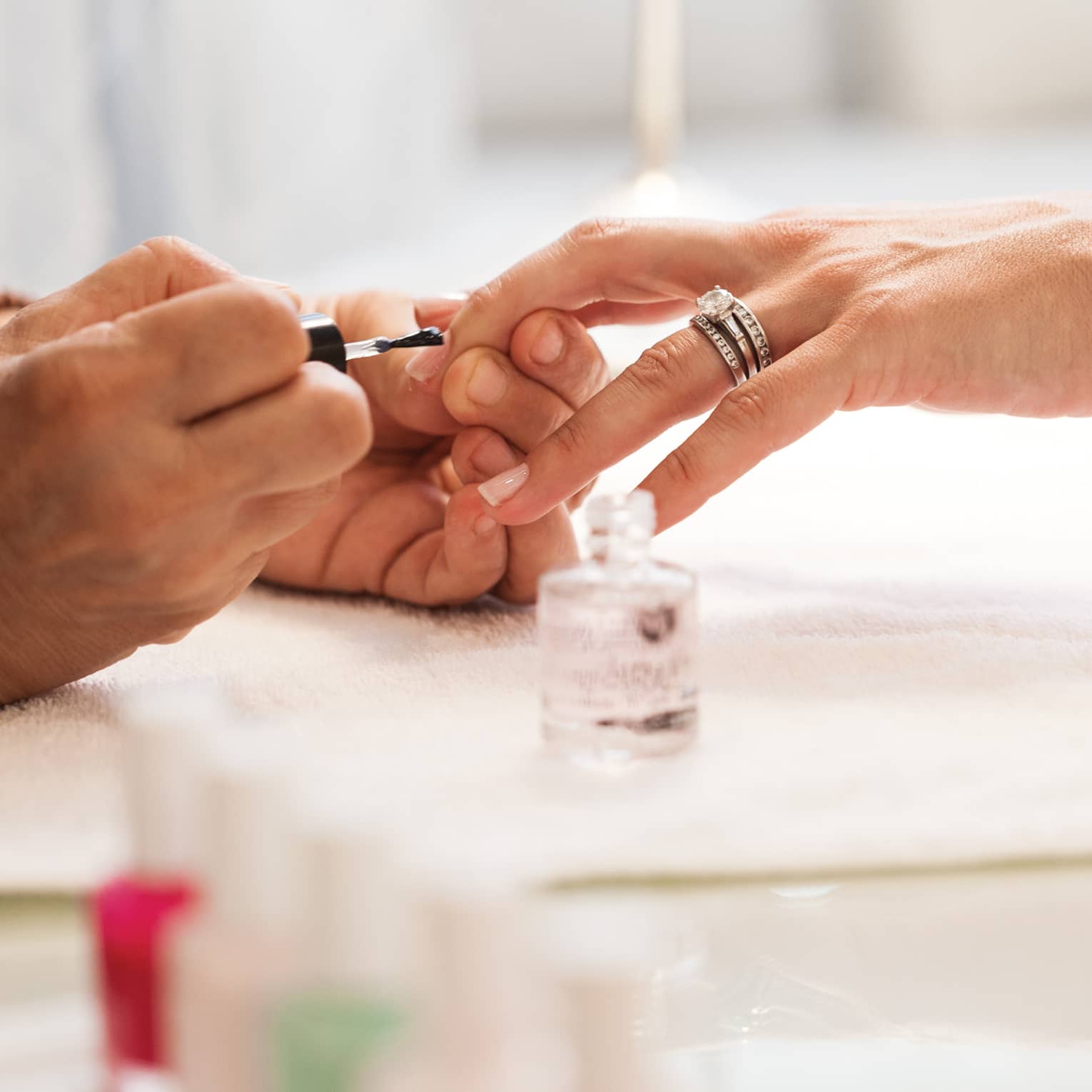 Close-up of woman in white robe getting clear polish manicure at spa table