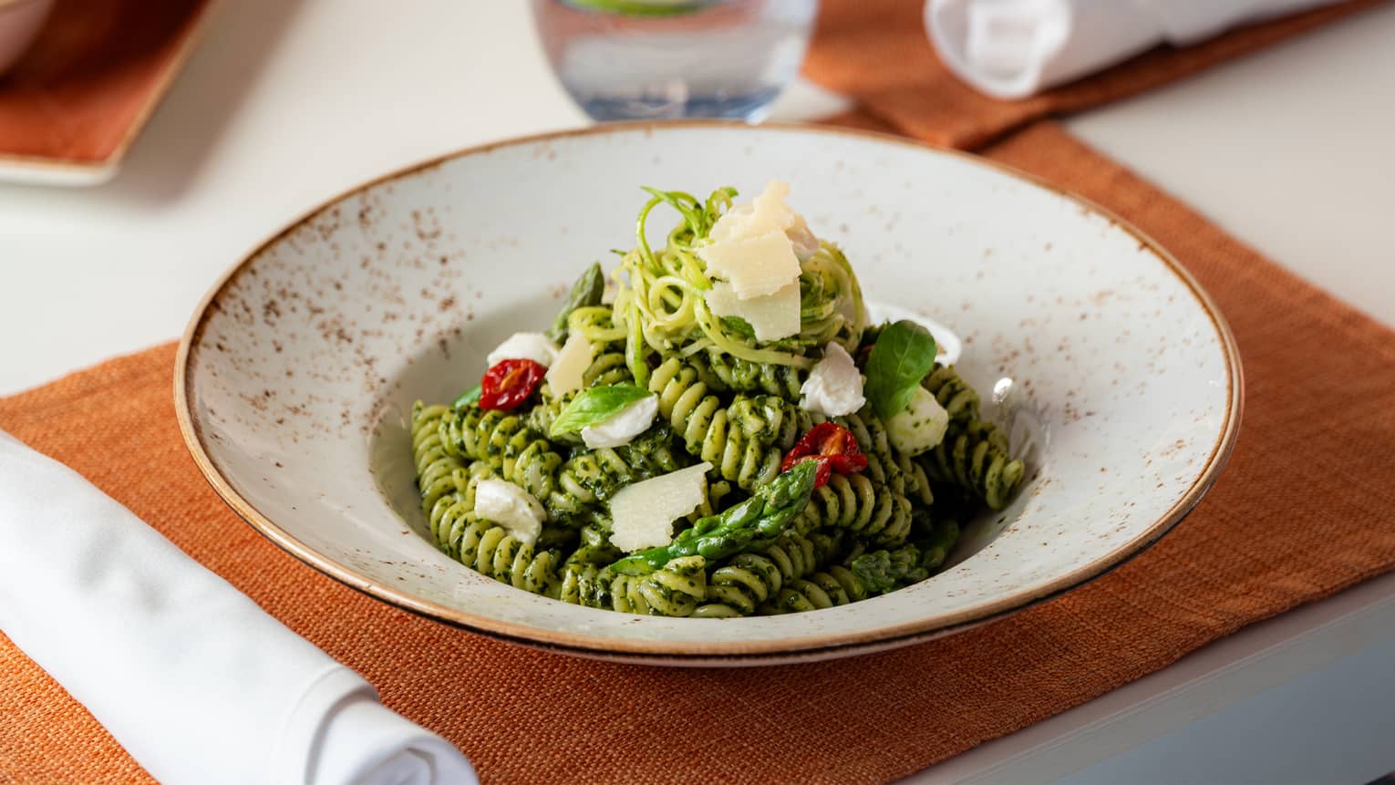 Fusilli pesto with asparagus, marrow, sun-dried tomatoes, buffalo mozzarella and pine nuts served in a white, gold-rimmed bowl