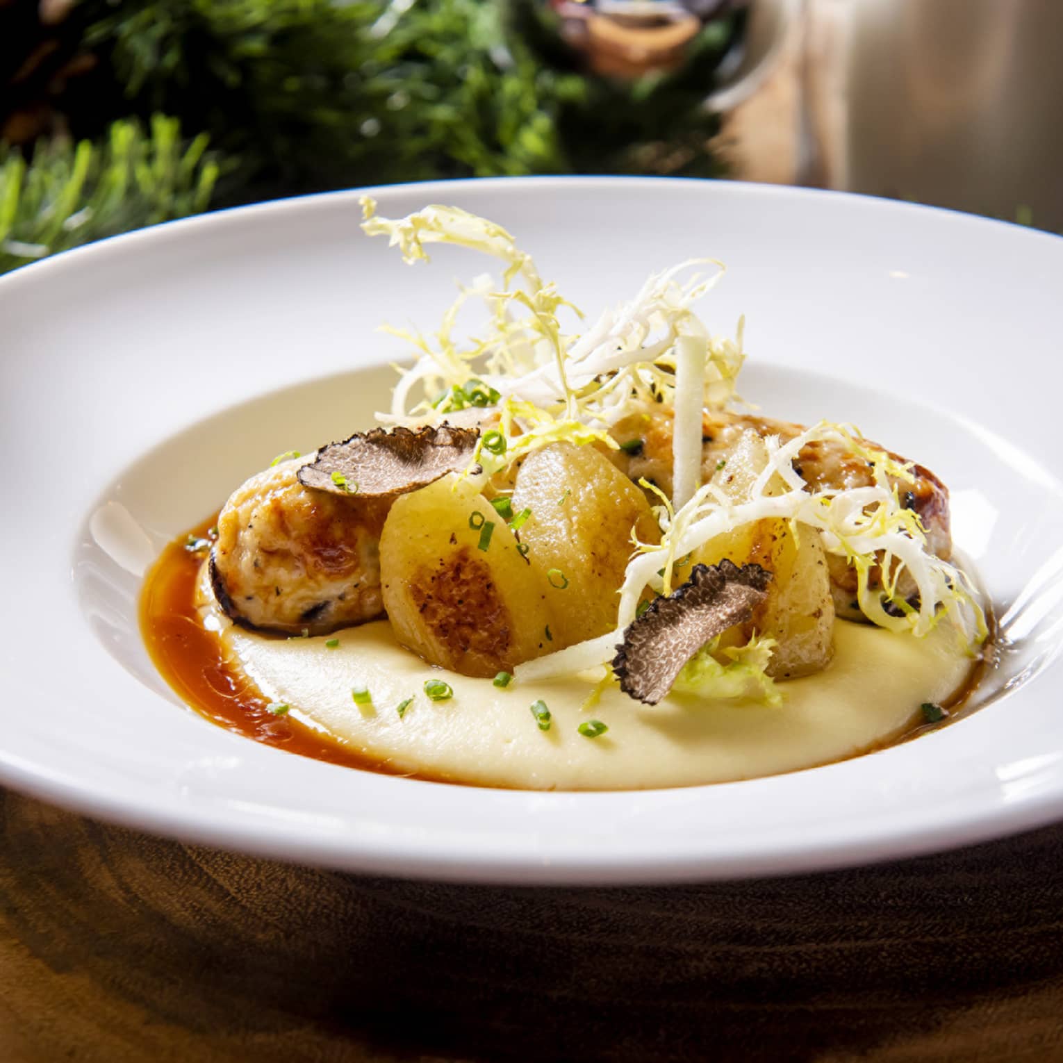 Scallops on polenta with shaved truffle and curly endive in white bowl