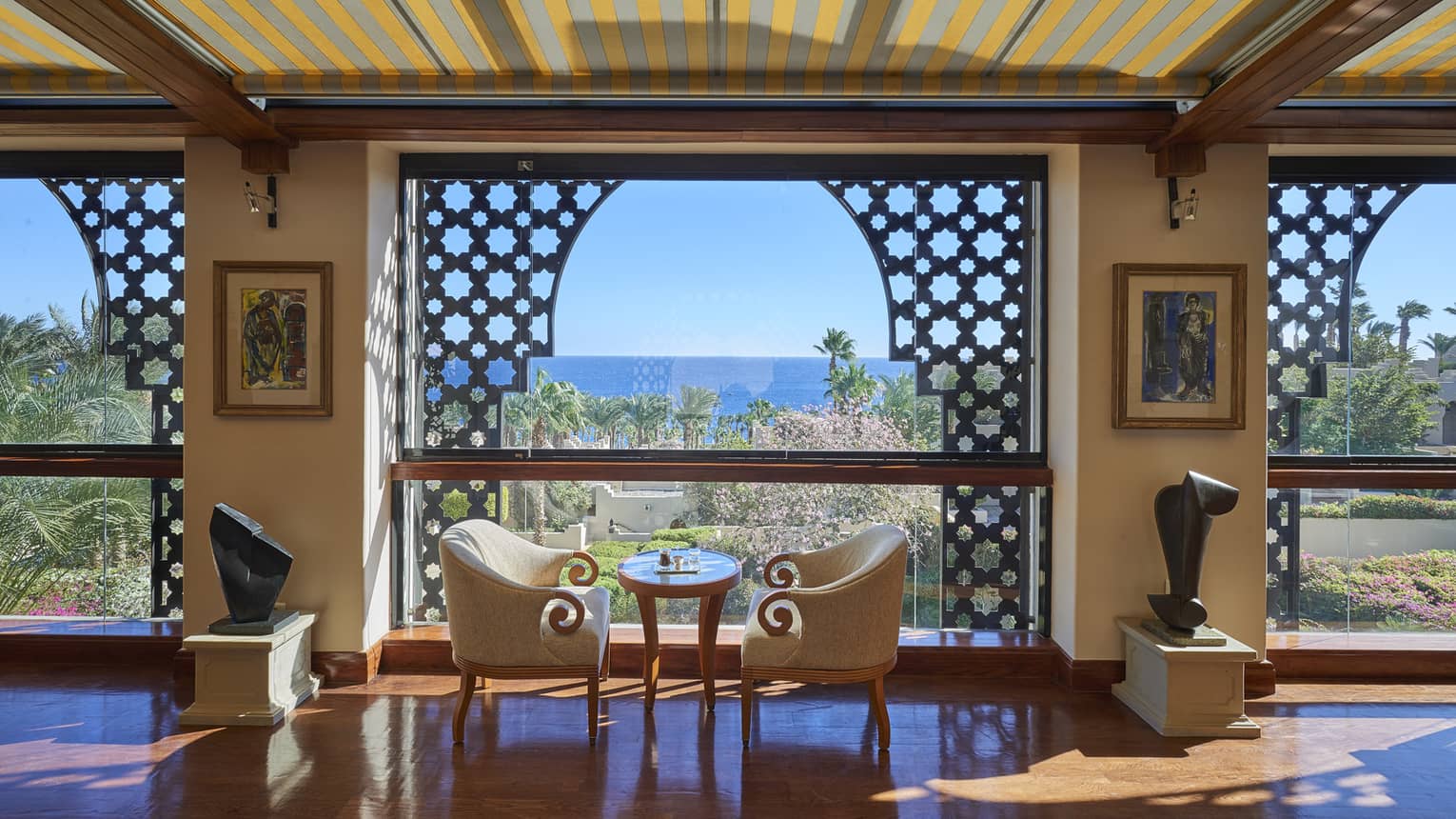 Observatory Lounge with small table and two club chairs, large arched window, ocean view