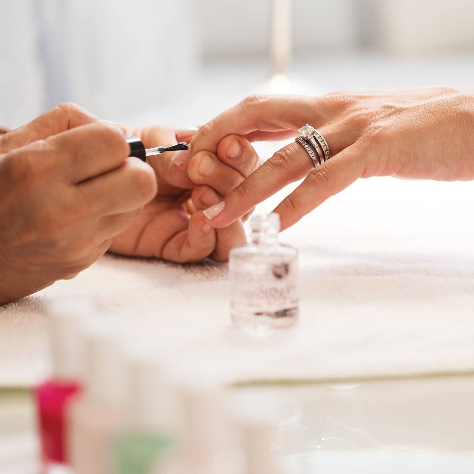 Close-up of woman in white robe getting clear polish manicure at spa table