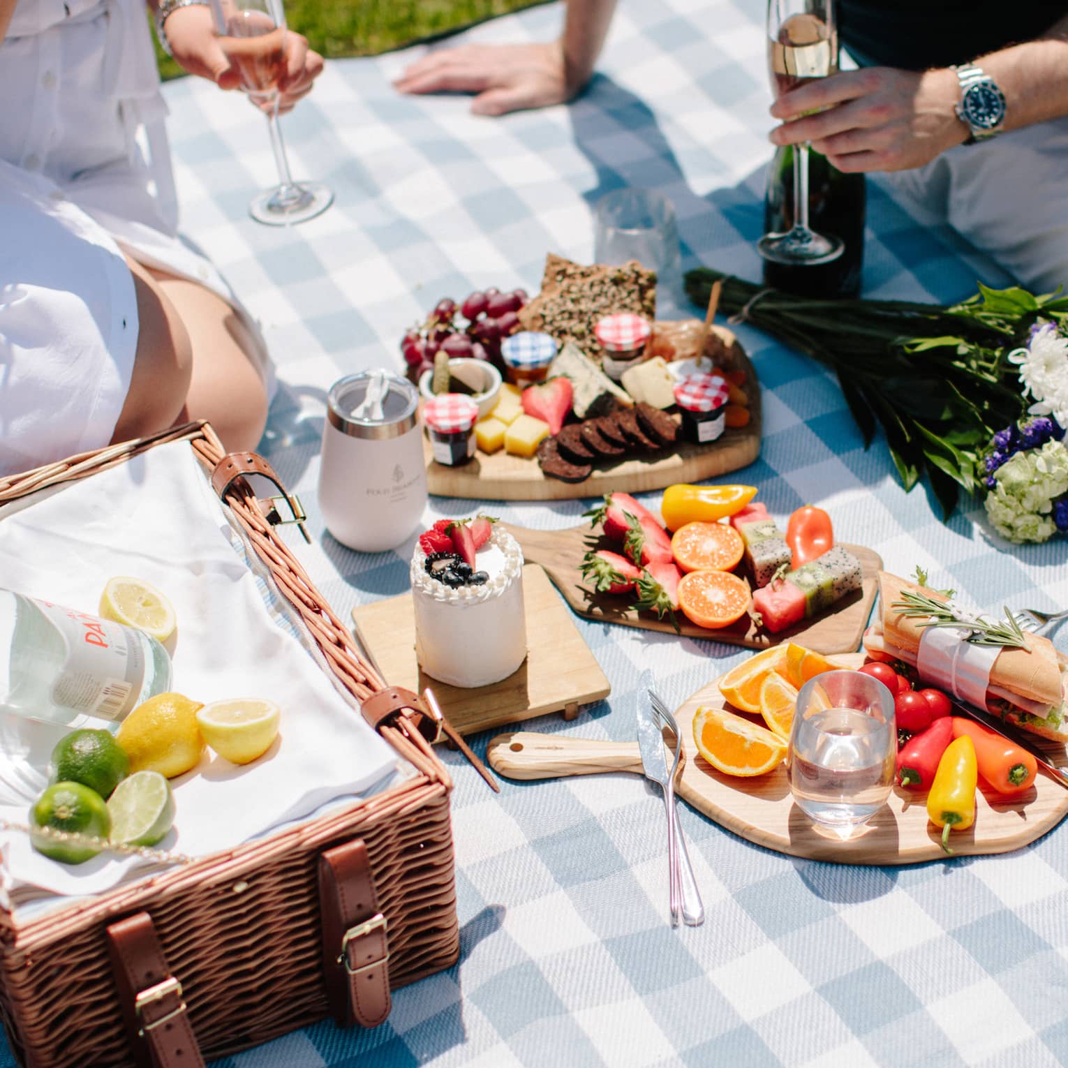 Two people enjoying a large picnic in a park during a sunny day.