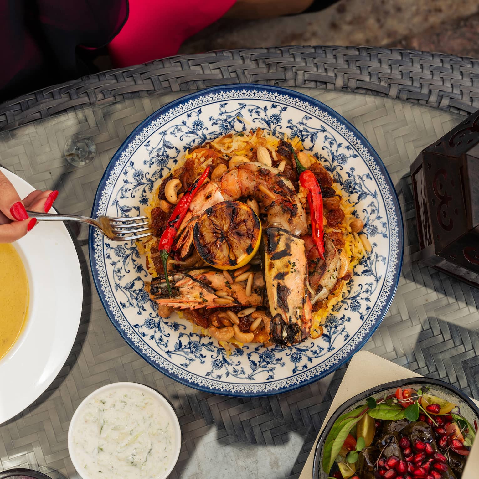 Deep gold risotto topped with grilled seafood, whole red chilis, raisins and nuts and a decorative grilled lemon slice.