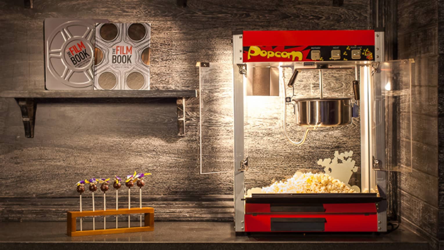 Popcorn machine, candy and film books on shelf in dark room