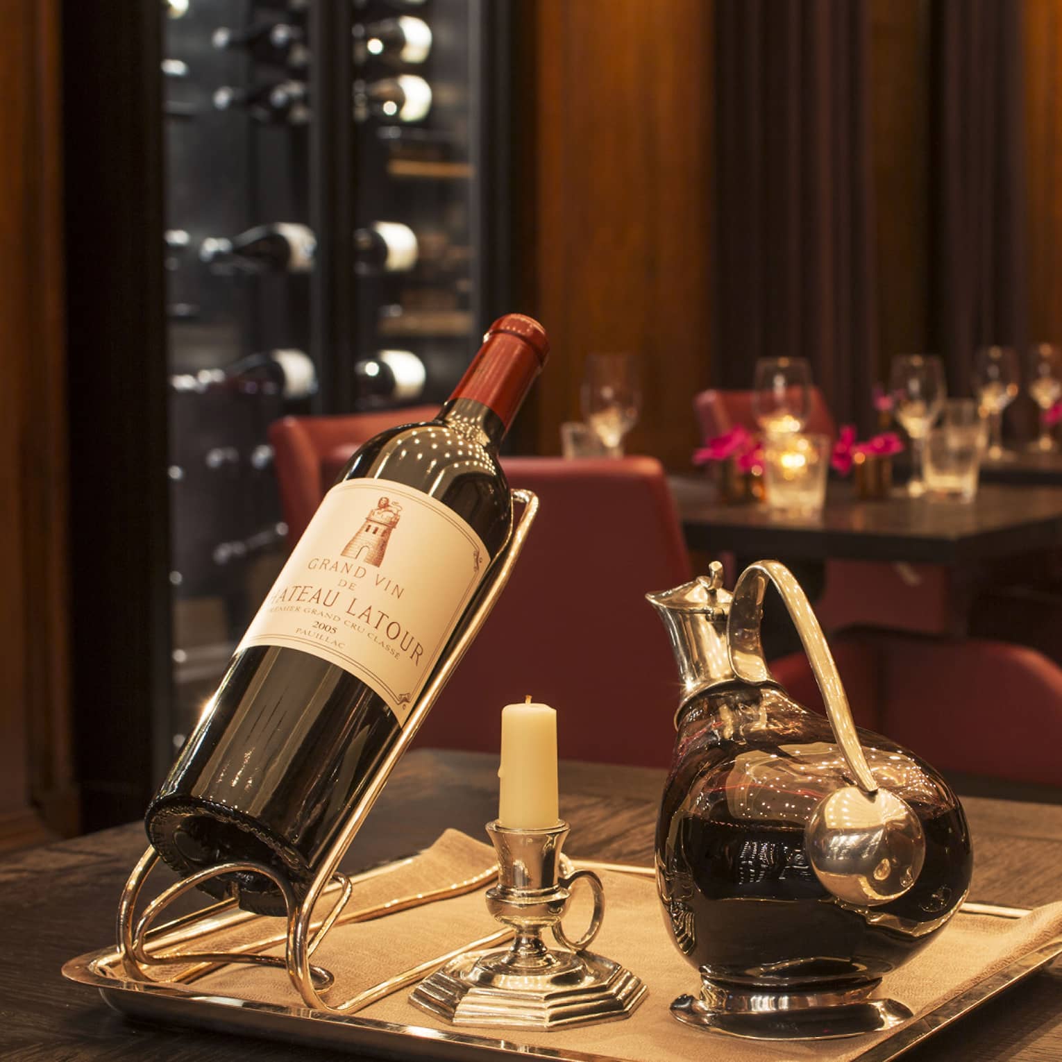 A bottle of red wine, a decanter and two glasses in a dimly lit restaurant.