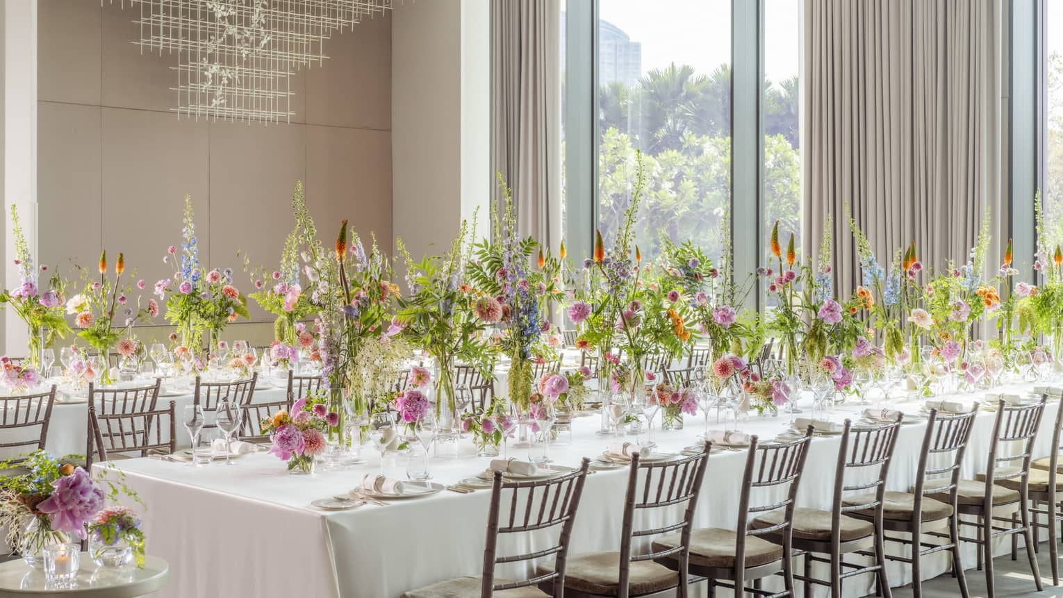 Ballroom set classroom-style with white linen?covered tables and tall floral centrepieces