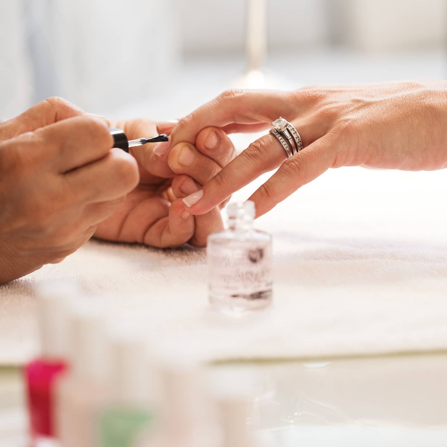 Close-up of woman in white robe getting clear polish manicure at spa table