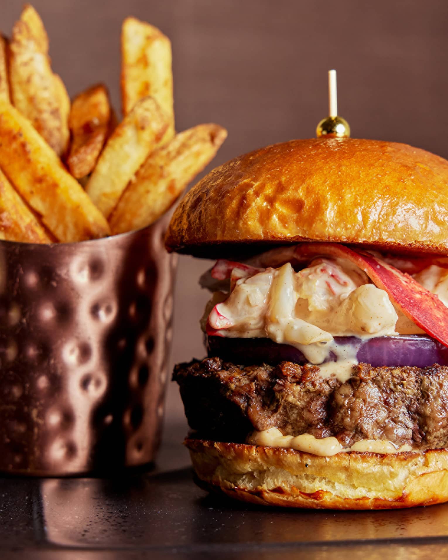 A burger and fries on a black plate.