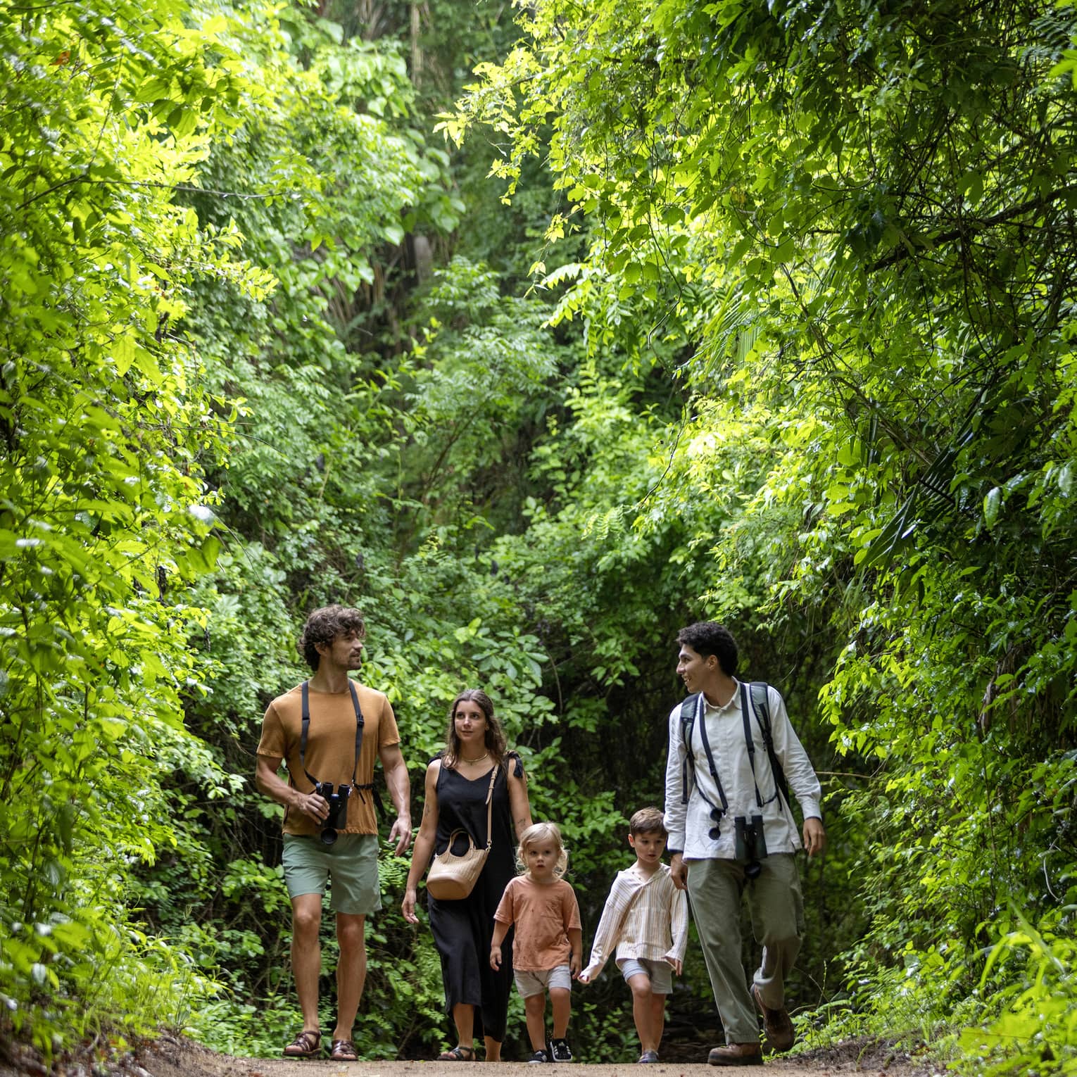 Three adults and two children walk in the forest
