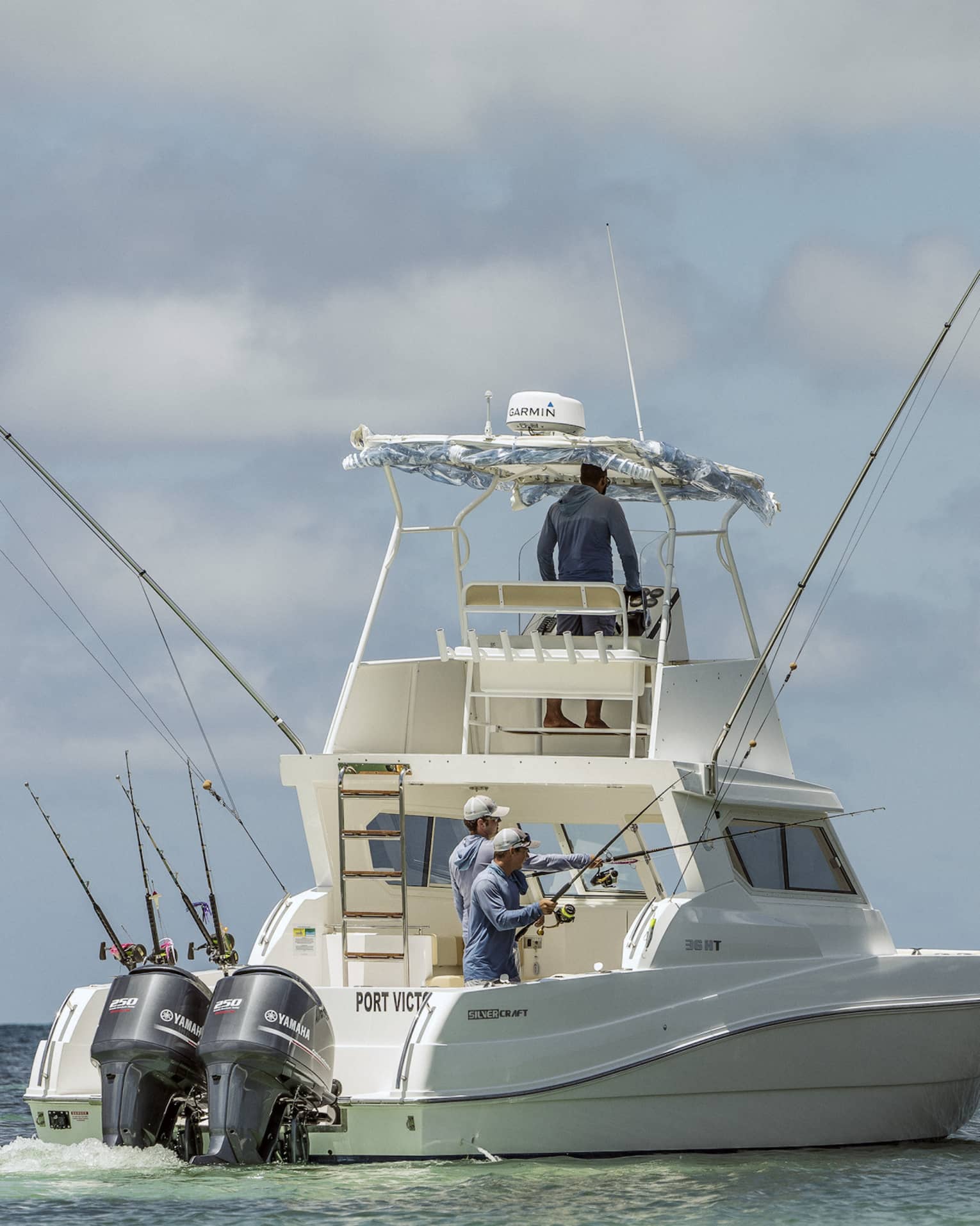 Two men fishing on the back of large white fishing boat