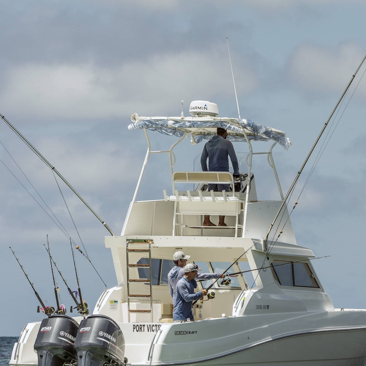 Two men fishing on the back of large white fishing boat