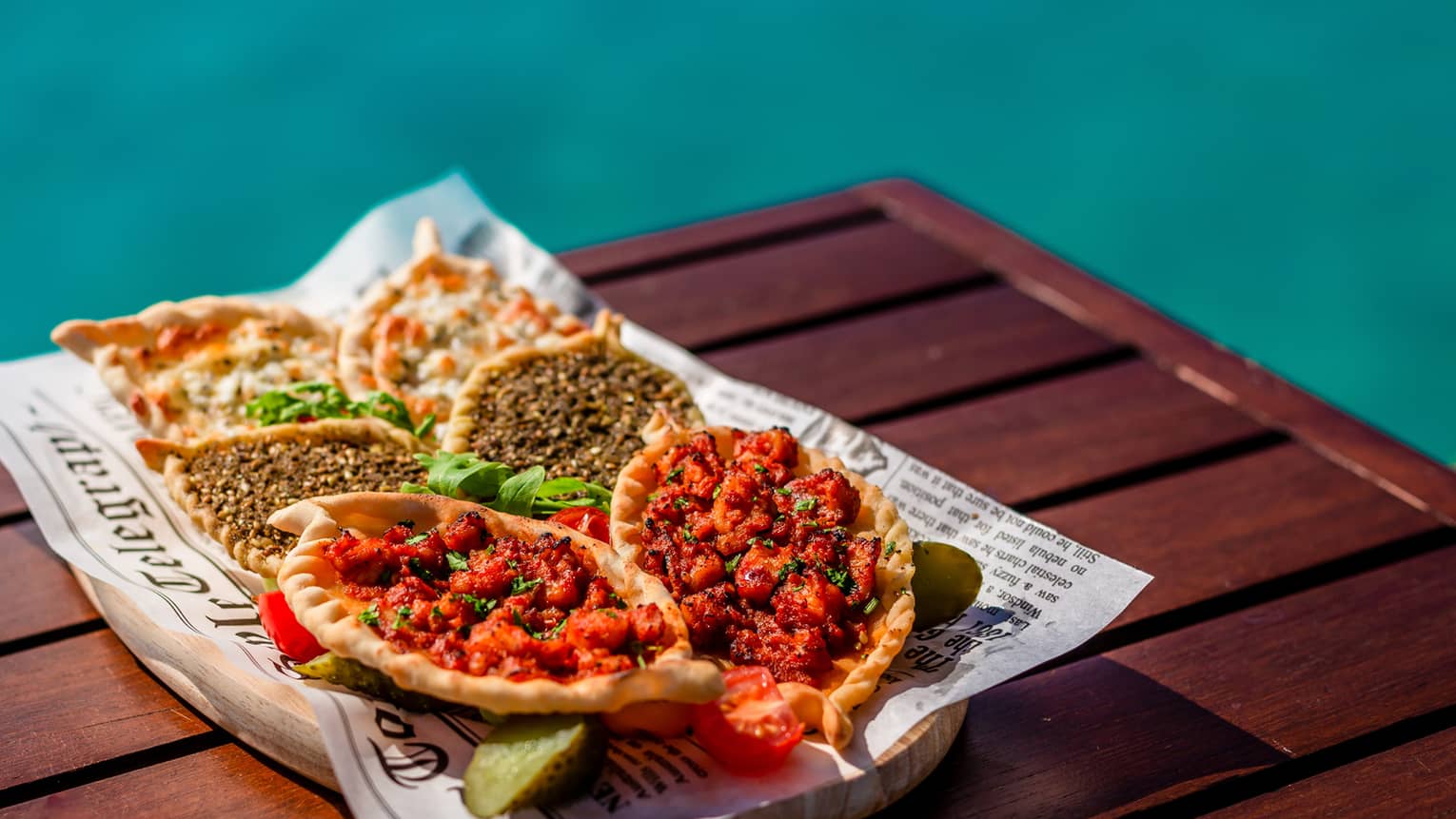 Manakish selection with levant pastry and various toppings on poolside table