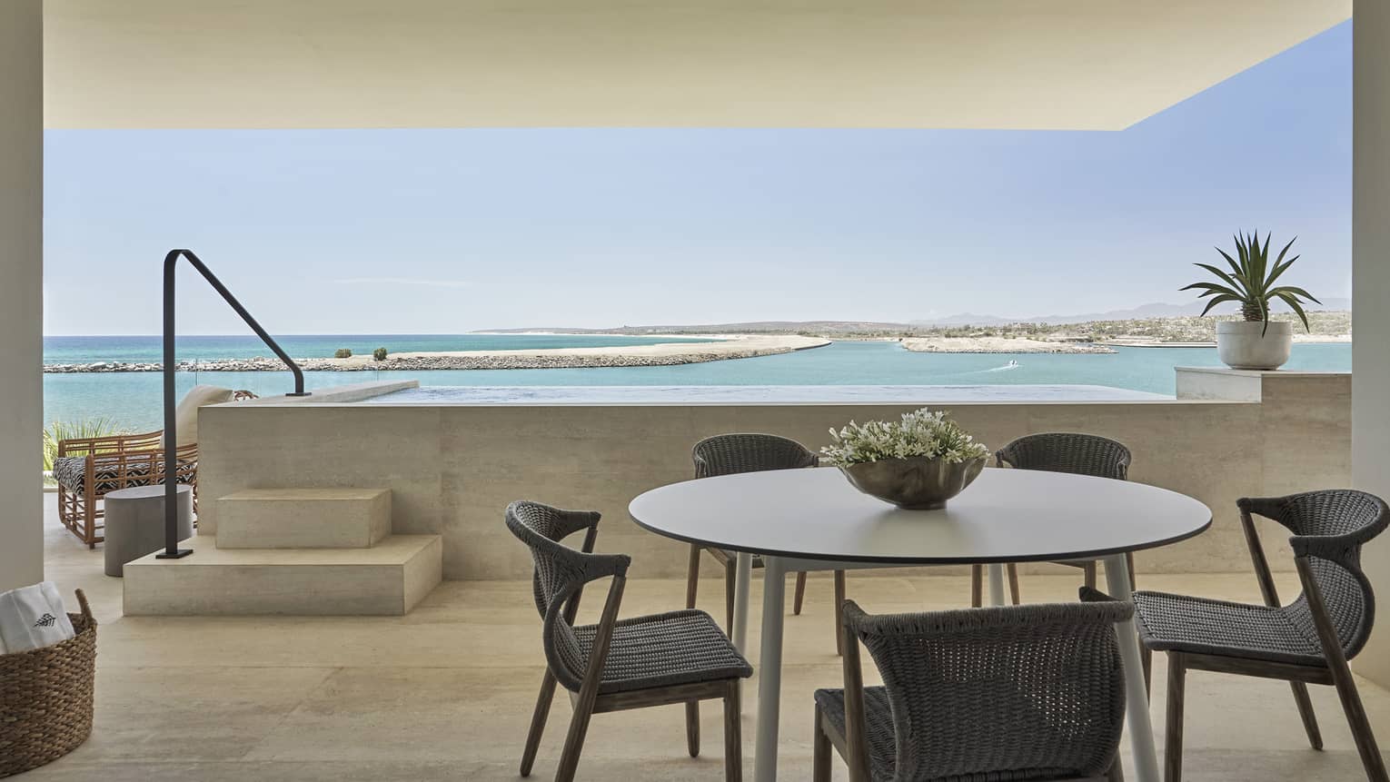 Large balcony, dining table with five dark whicker chairs, plunge pool, sea view
