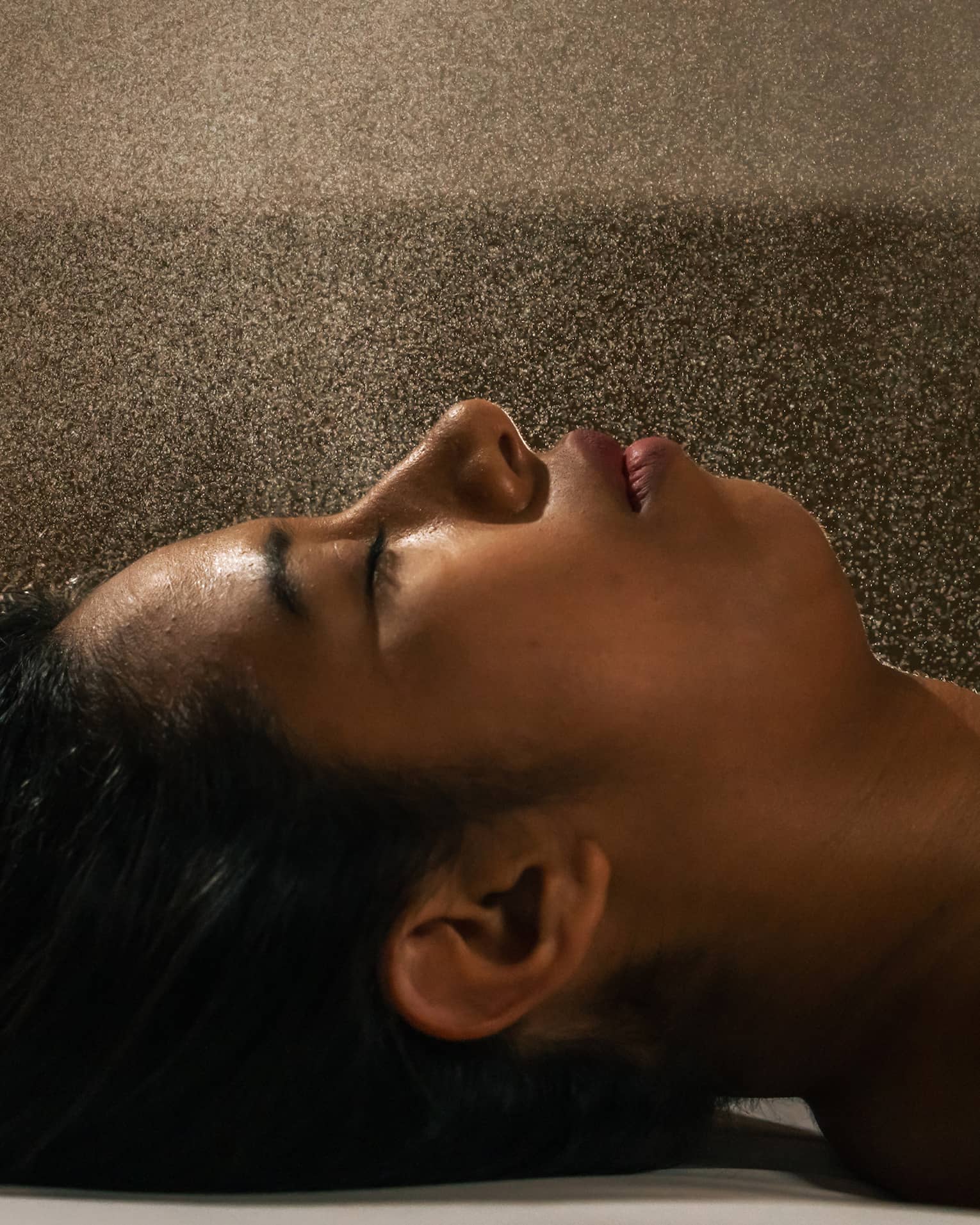 Close up of head and shoulders of person lying down with eyes closed on a spa massage table