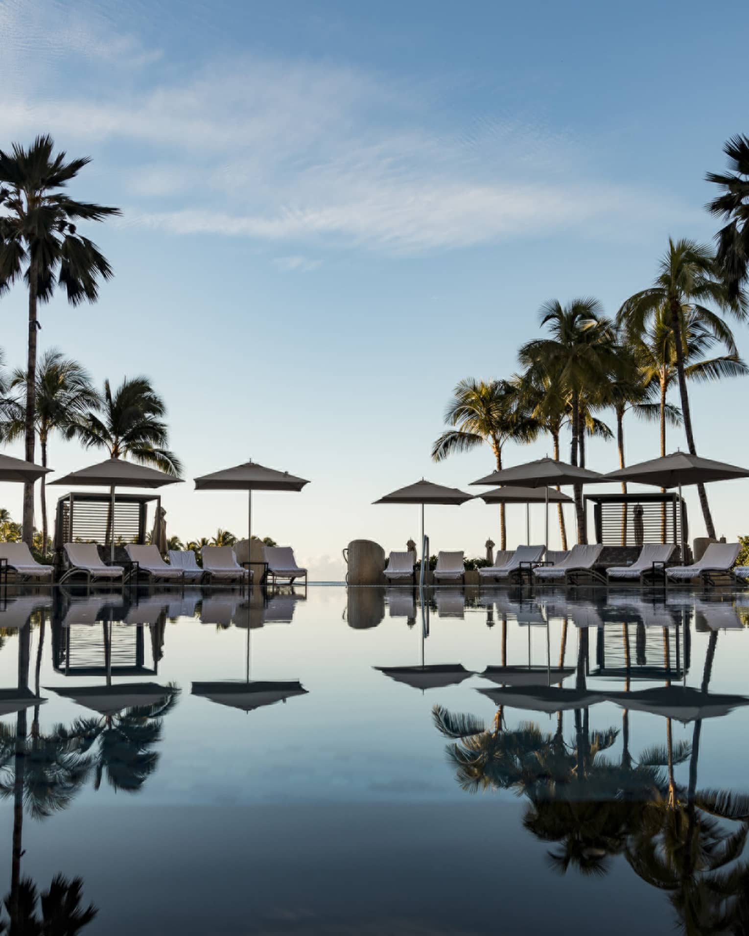 Large pool reflecting the palm trees and lounge chairs around it
