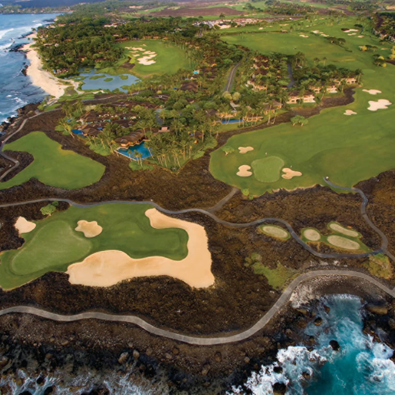 Aerial view of Hualalai Golf Course along rocky shore and ocean