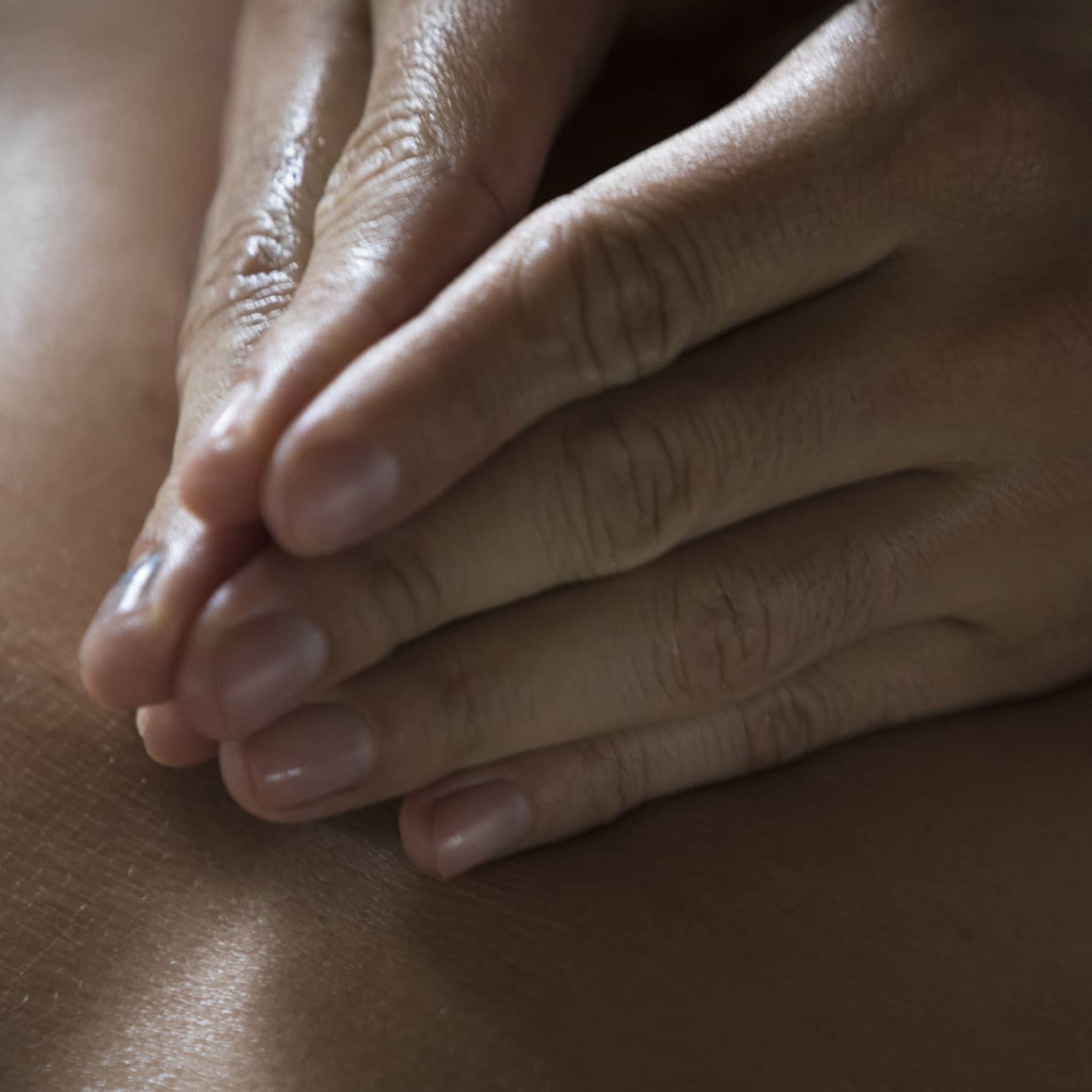 Two hands massage a person's back