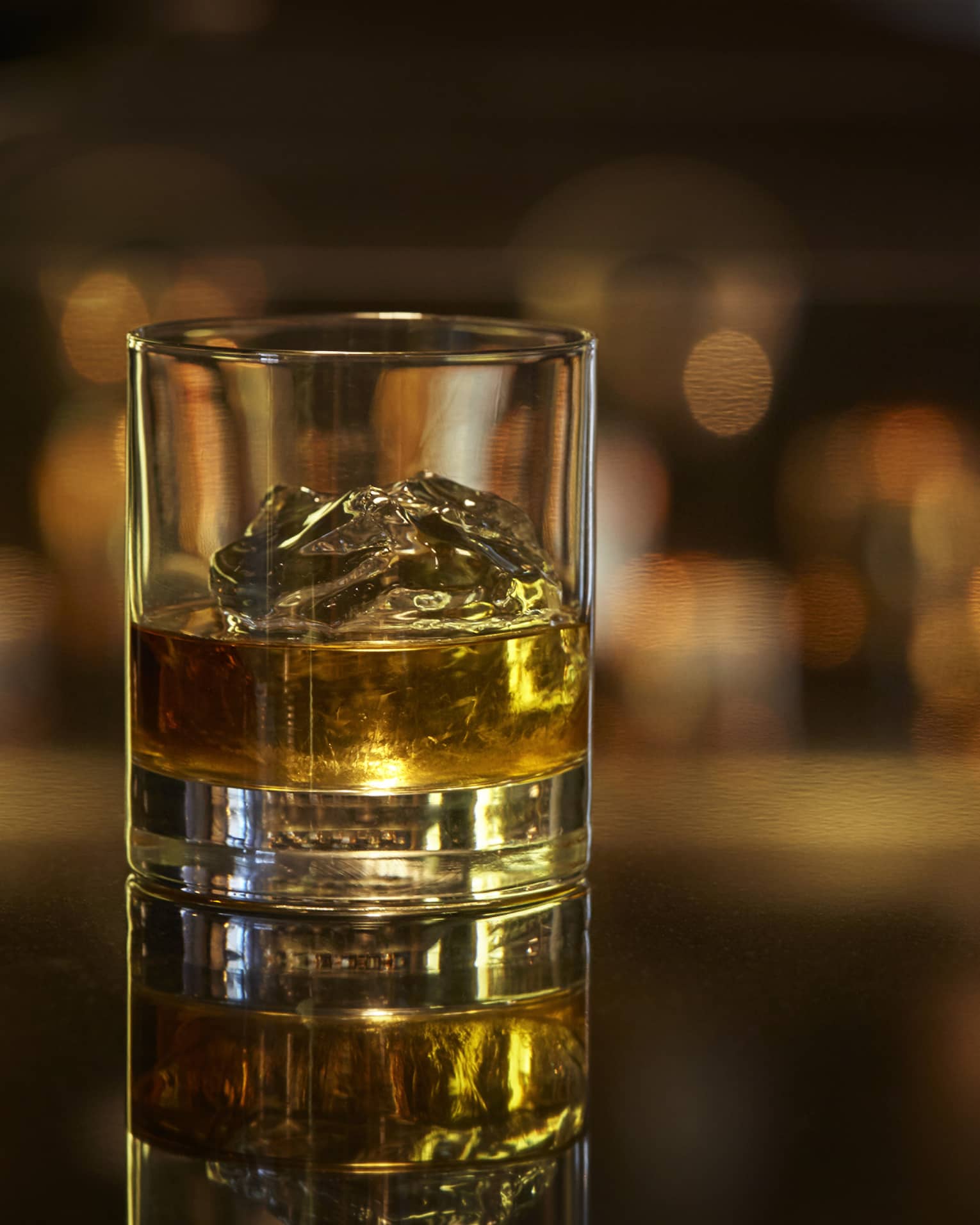 Scotch on the rocks, liquor on ice cubes in rock glass on bar 