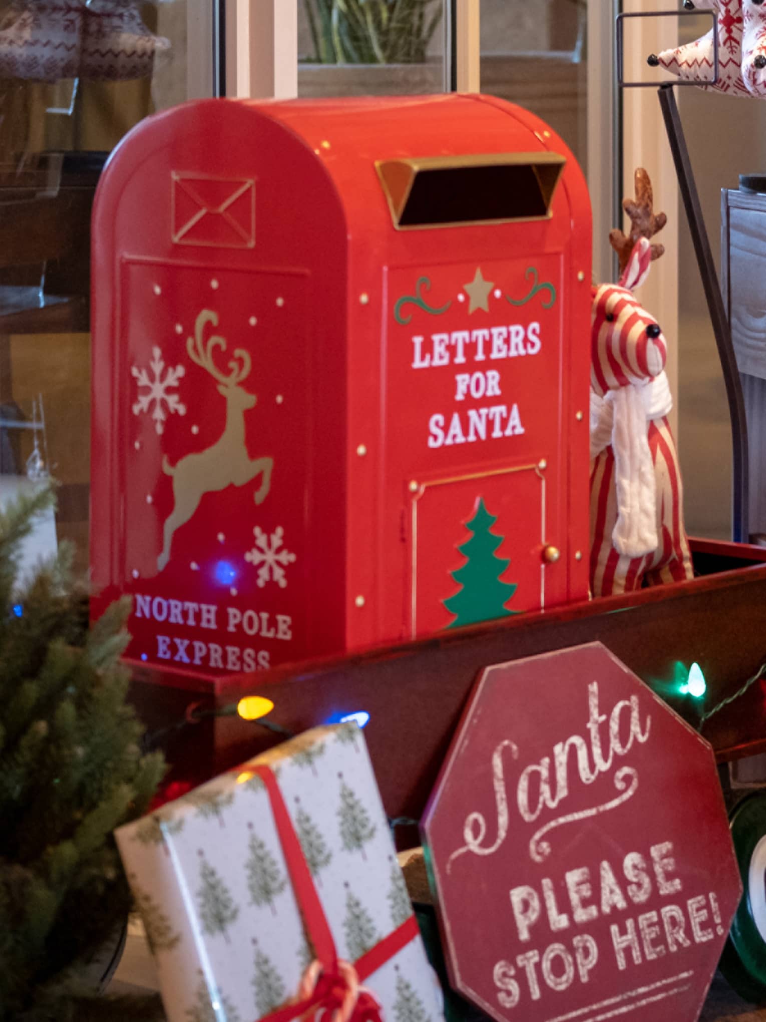 A young boy sits at a desk with presents around it and writes a letter to santa