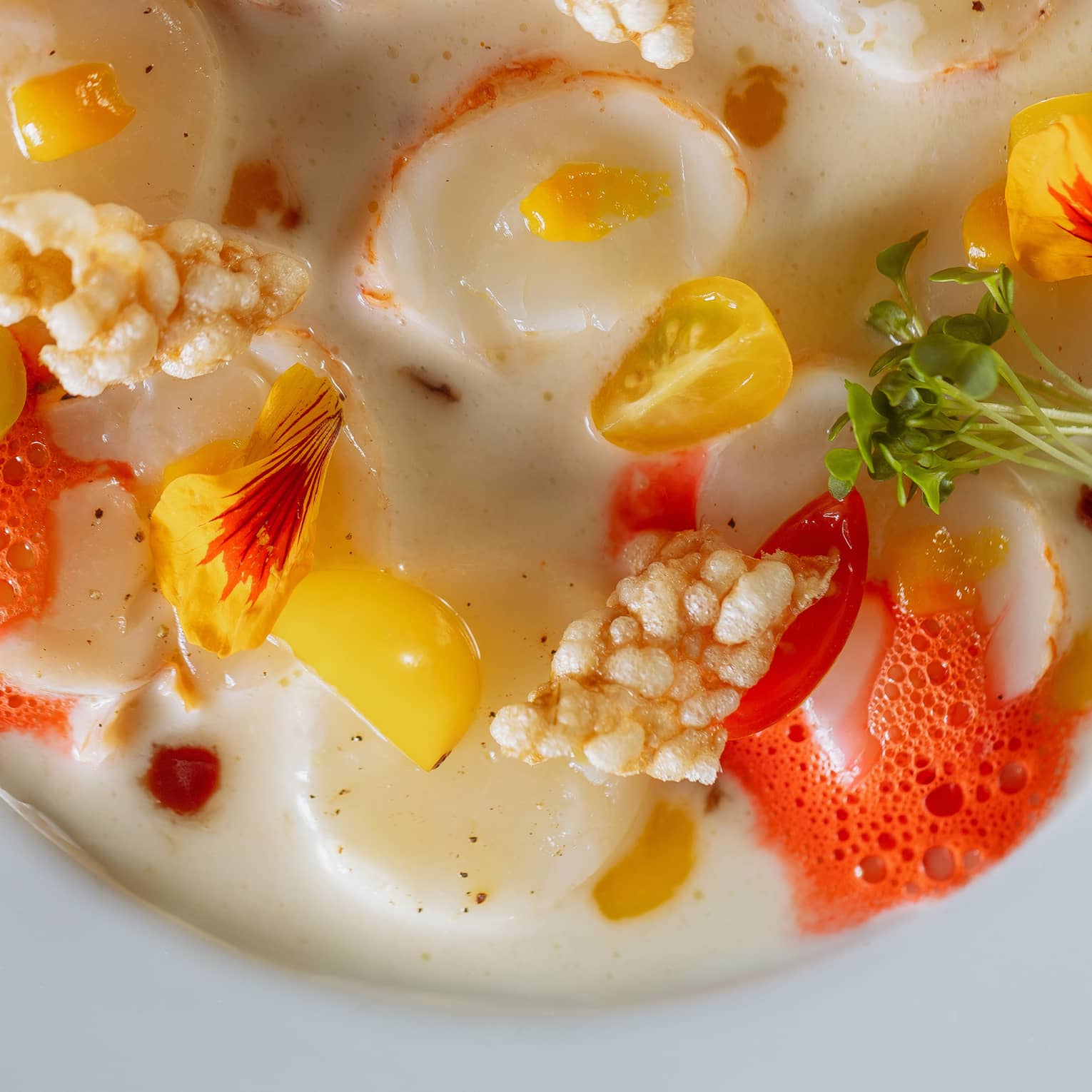 Seafood chowder garnished with chillies and microgreens