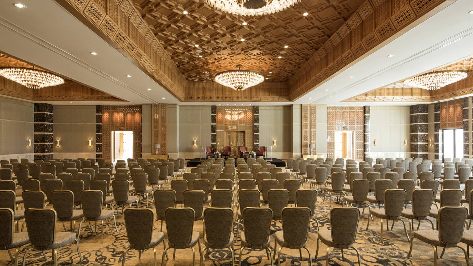Chairs arranged in rows in Jasmin Ballroom accented with gold and large chandeliers