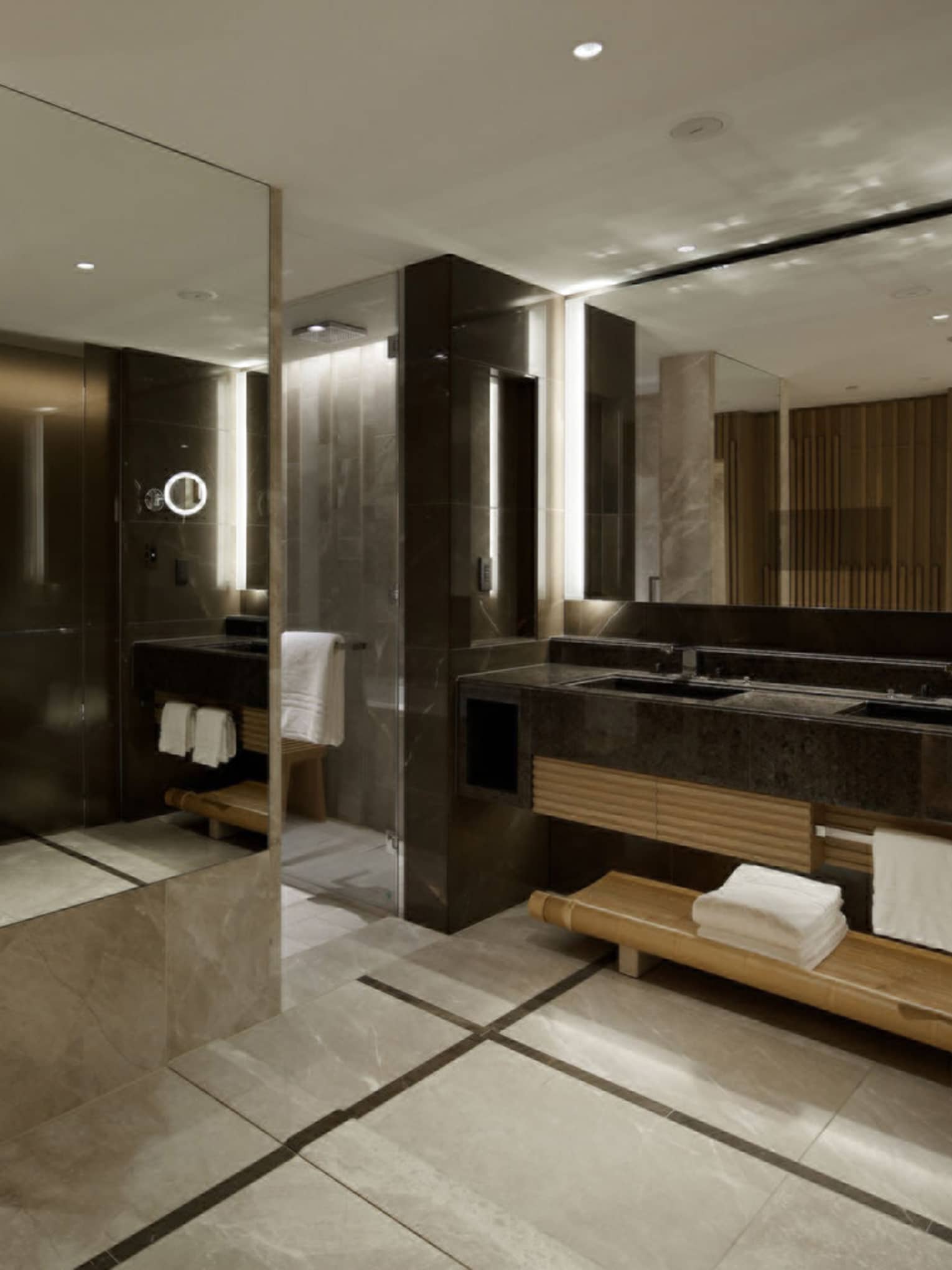 Spacious bathroom with a double-sink vanity, large mirrors and marble wall accents, connecting to the bedroom