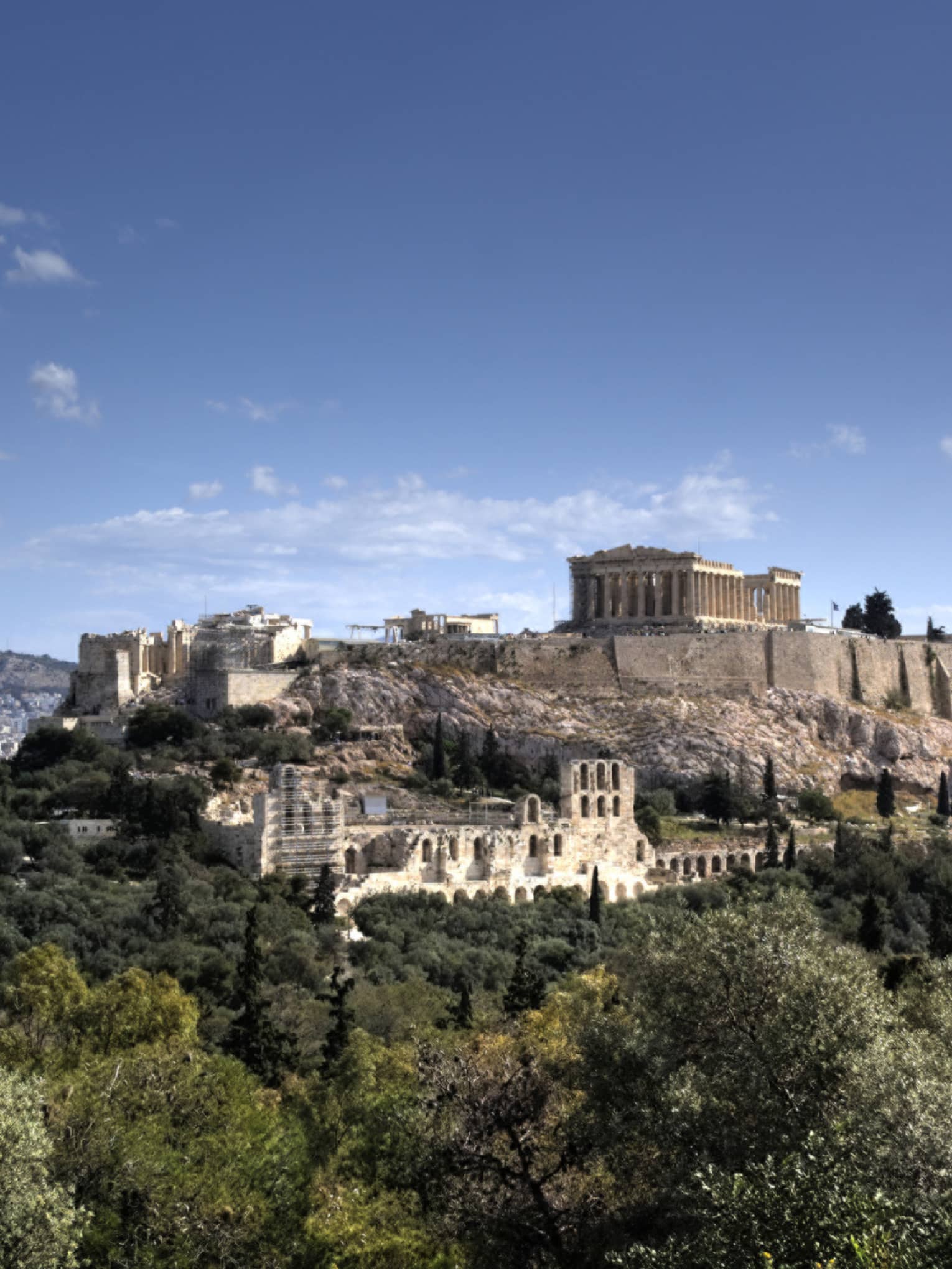 Ancient ruins of Acropolis on mountain surrounded by greenery